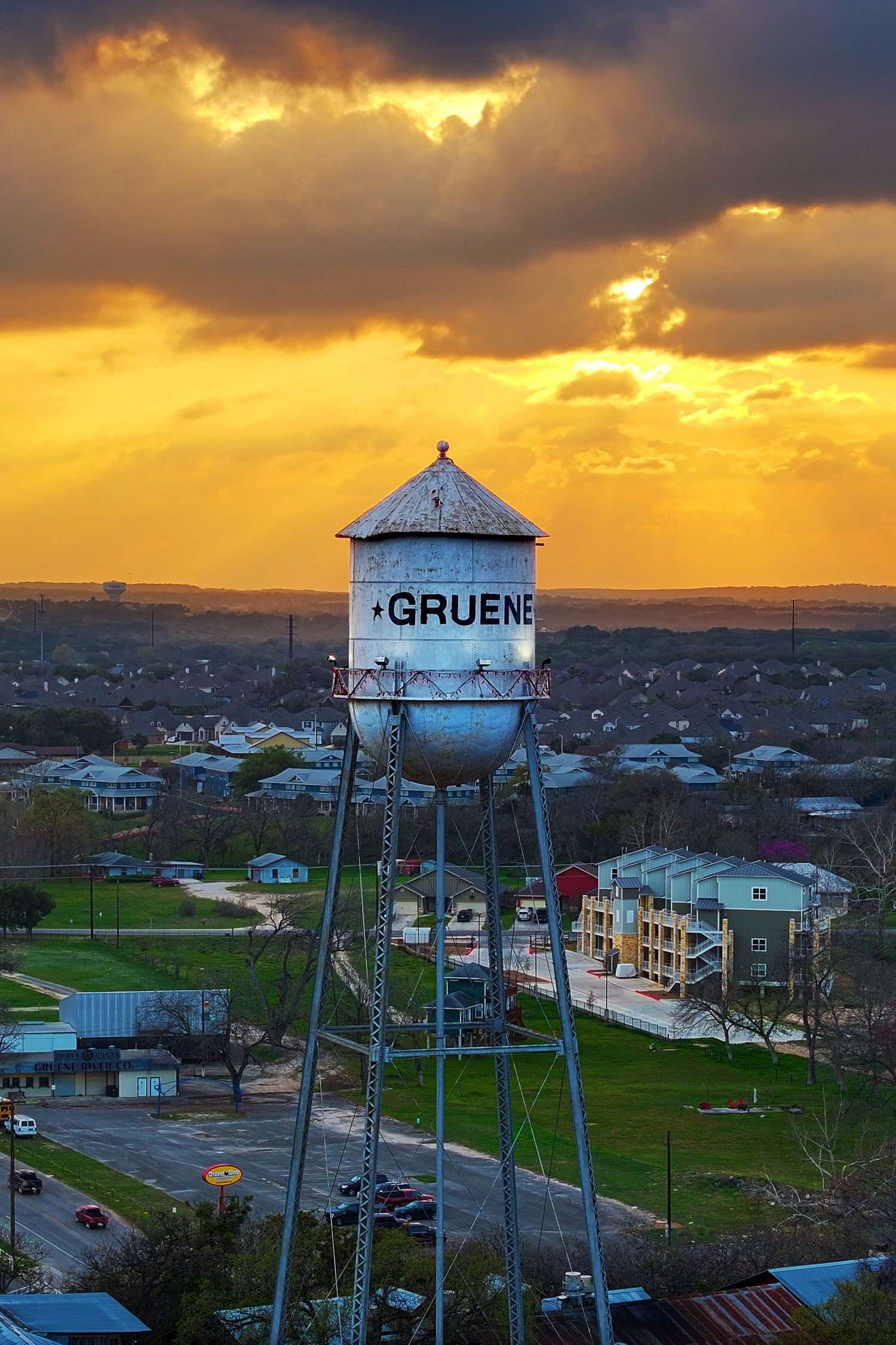 Gruene water tower at golden sunset with dramatic clouds over the historic Gruene, Texas skyline.