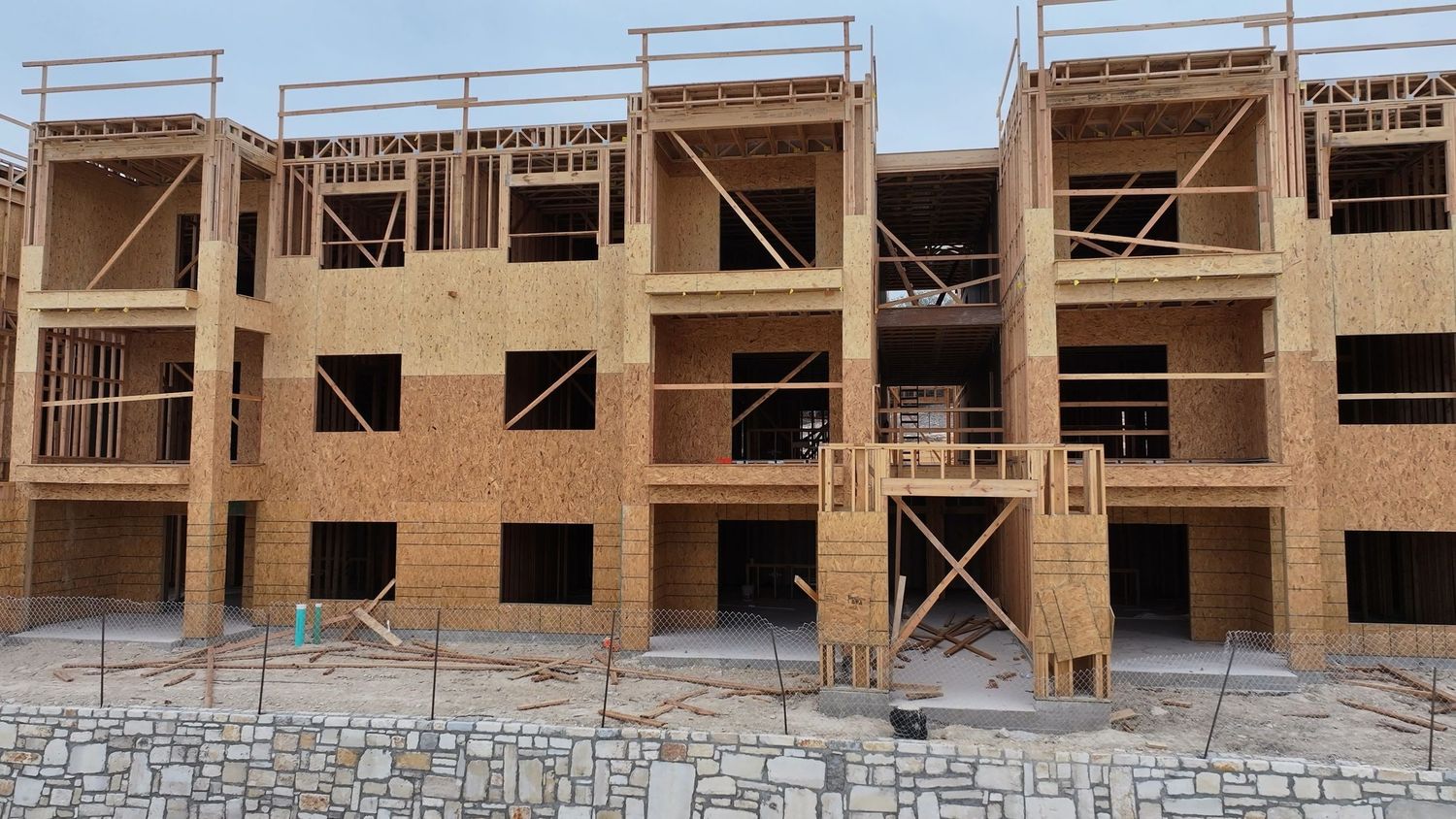 Multi-story residential apartment building under construction with wood framing and OSB sheathing on exterior walls.