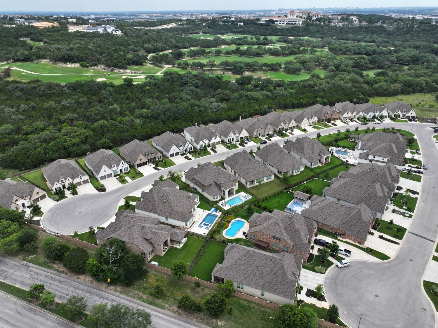 Aerial view of a small residential community with small homes, and lush greenery near a Cedar Creek golf course.