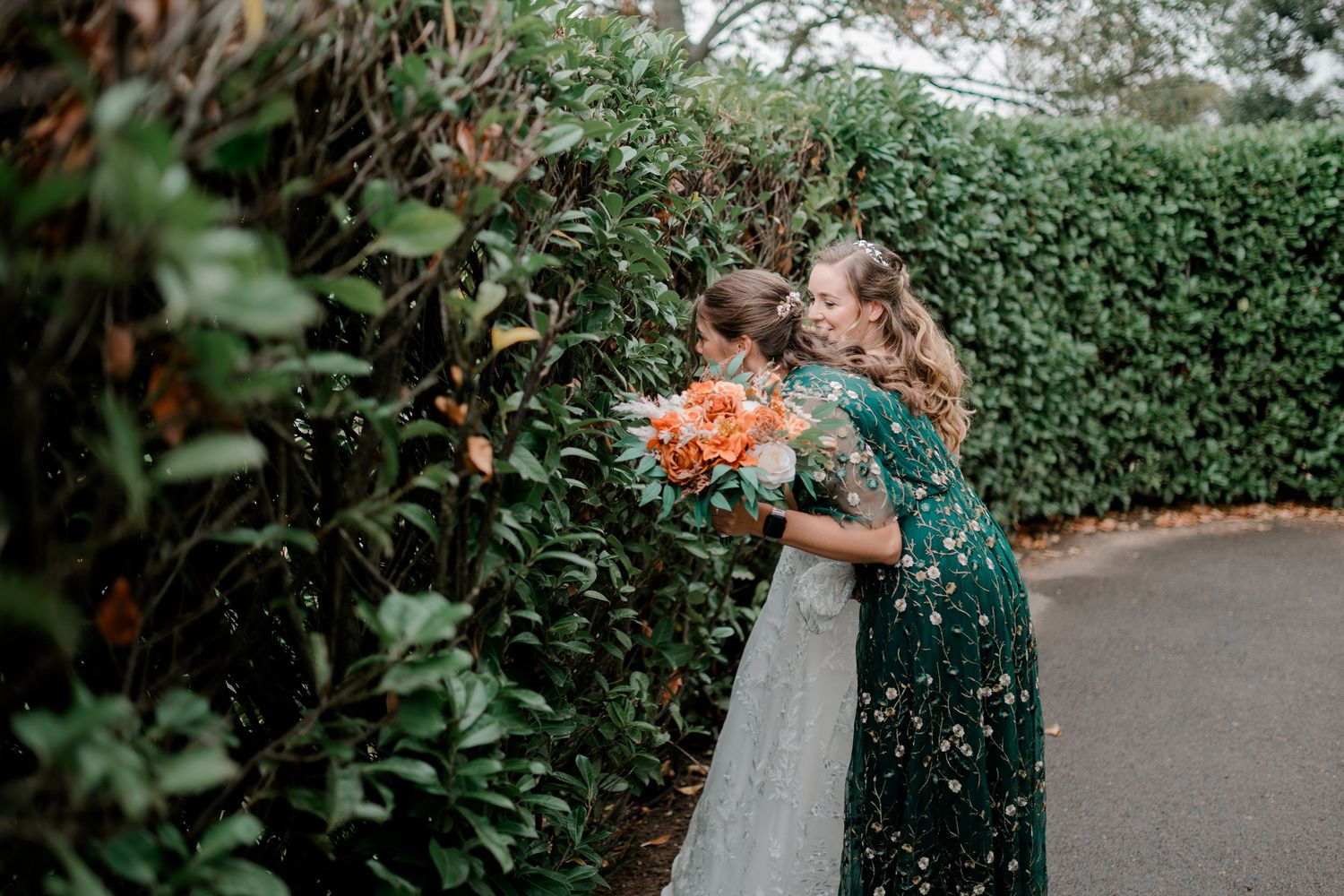 A couple shares an intimate embrace in a garden setting surrounded by lush greenery and foliage.
