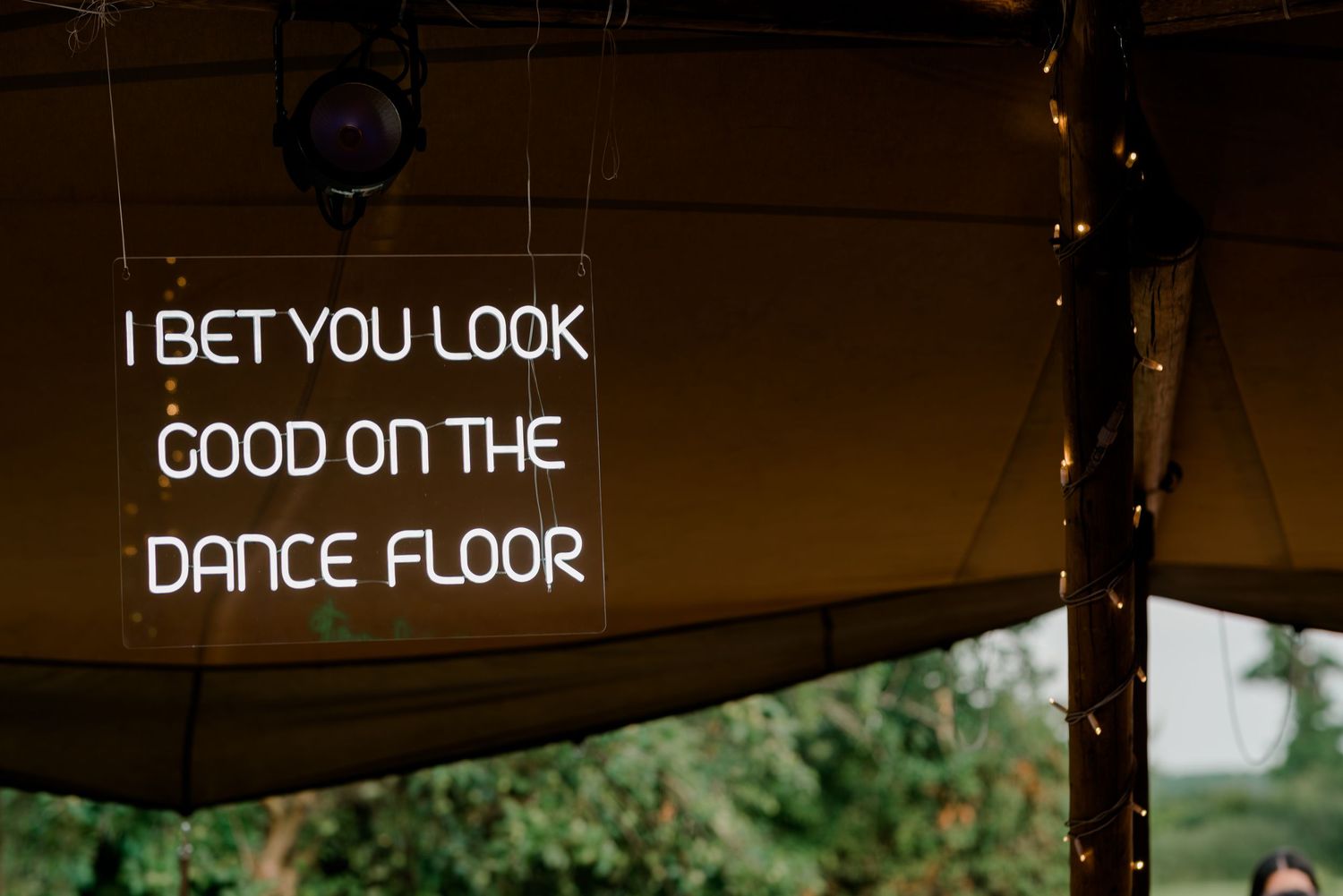 A dimly lit storefront sign reads 'I BET YOU LOOK GOOD ON THE DANCE FLOOR' in bright white lettering.