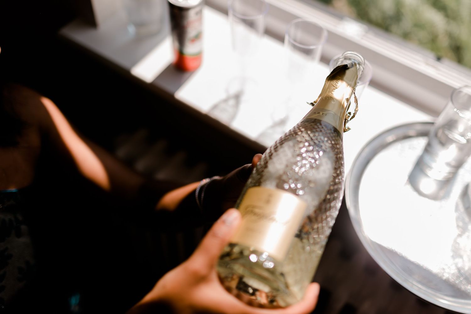 Frosty glass bottle with condensation being held in front of a window during daytime.