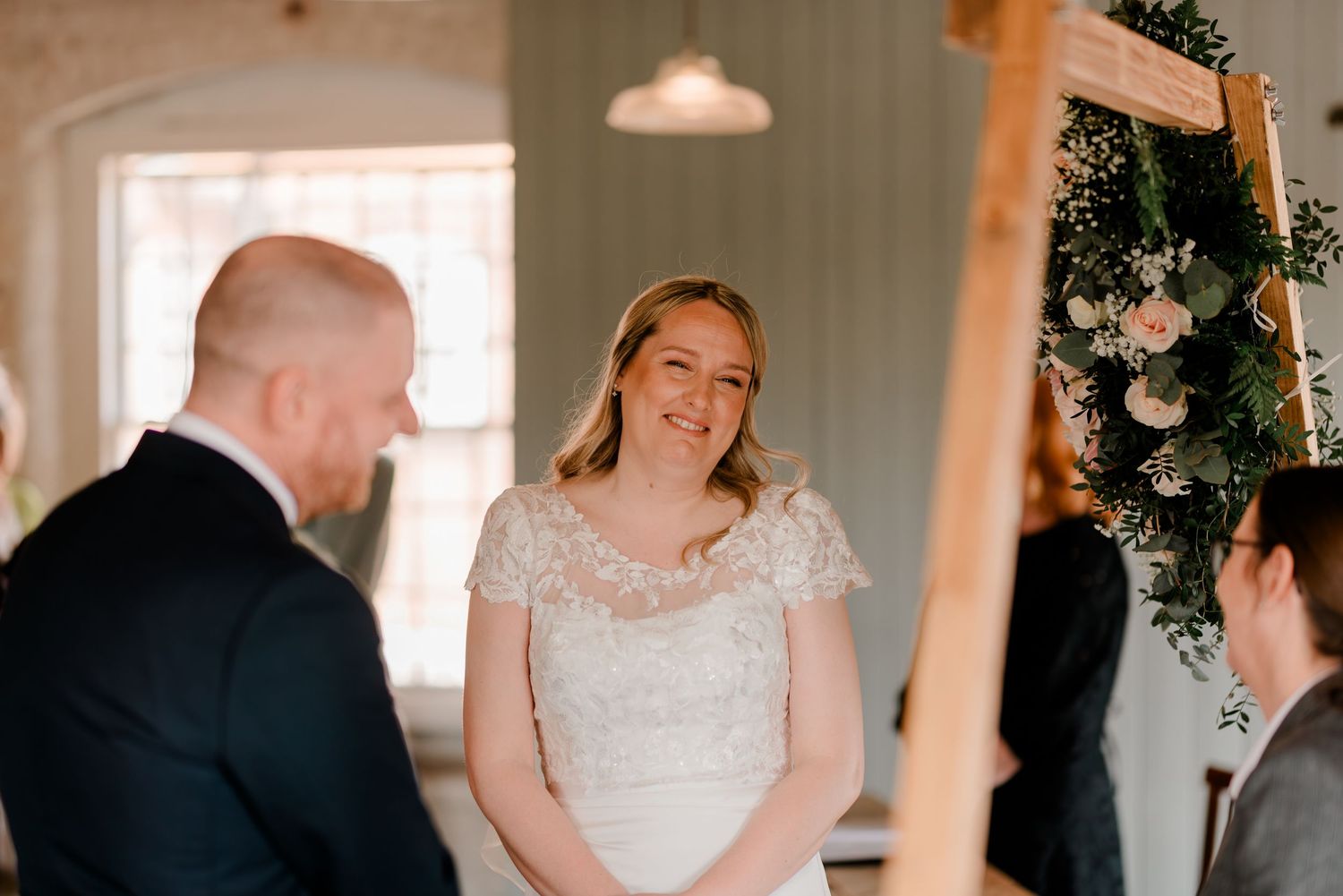 A joyful wedding ceremony moment in a rustic indoor venue with floral decorations.
