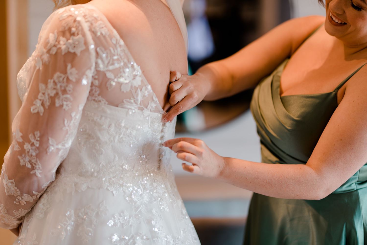 Close-up of intricate lace details being adjusted on a wedding dress.