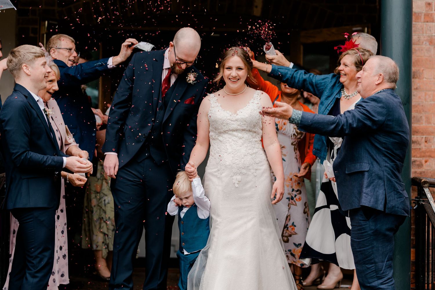 Guests celebrate by tossing confetti over a couple exiting a wedding ceremony.