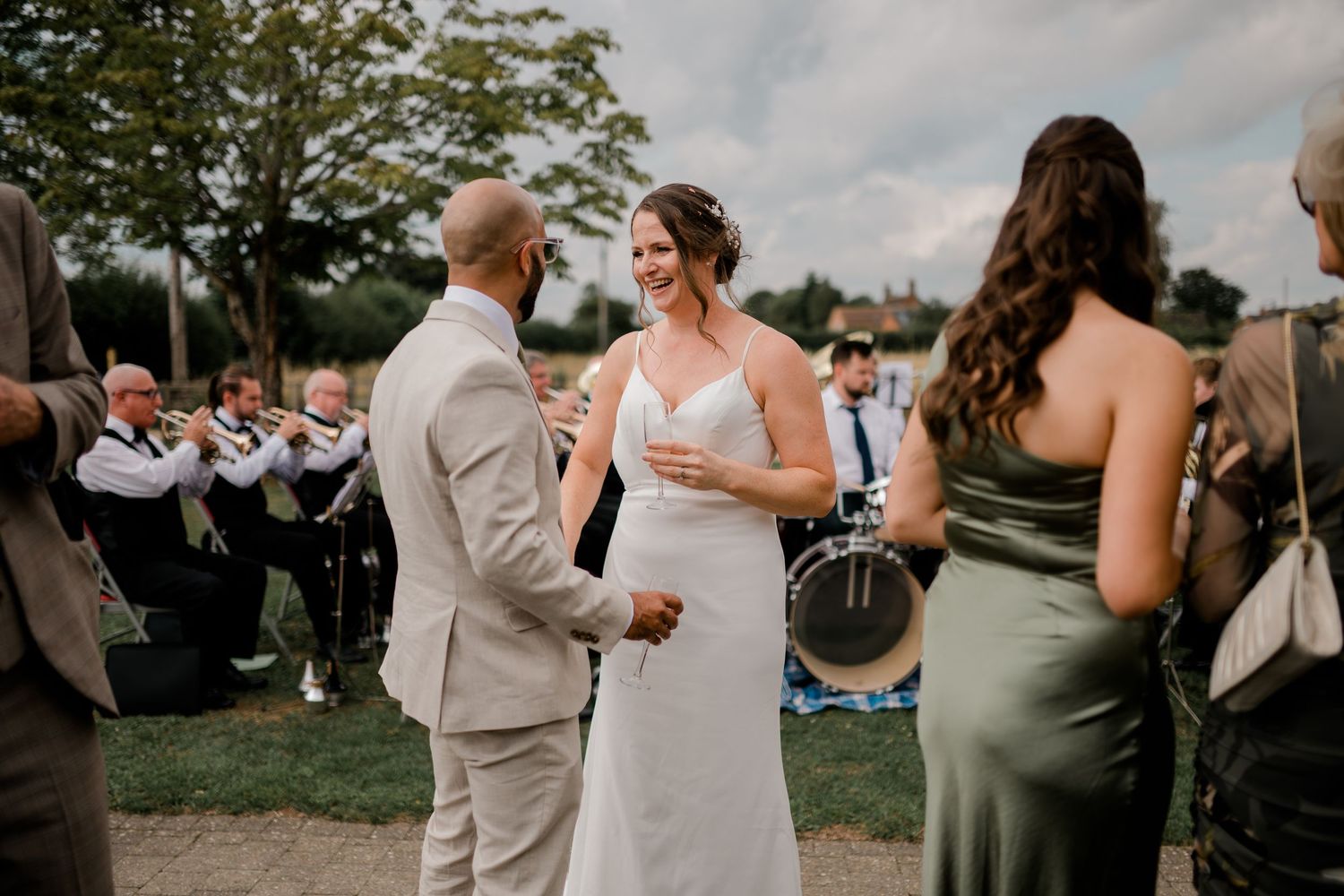 Wedding guests mingle on a grassy lawn during an outdoor summer celebration.