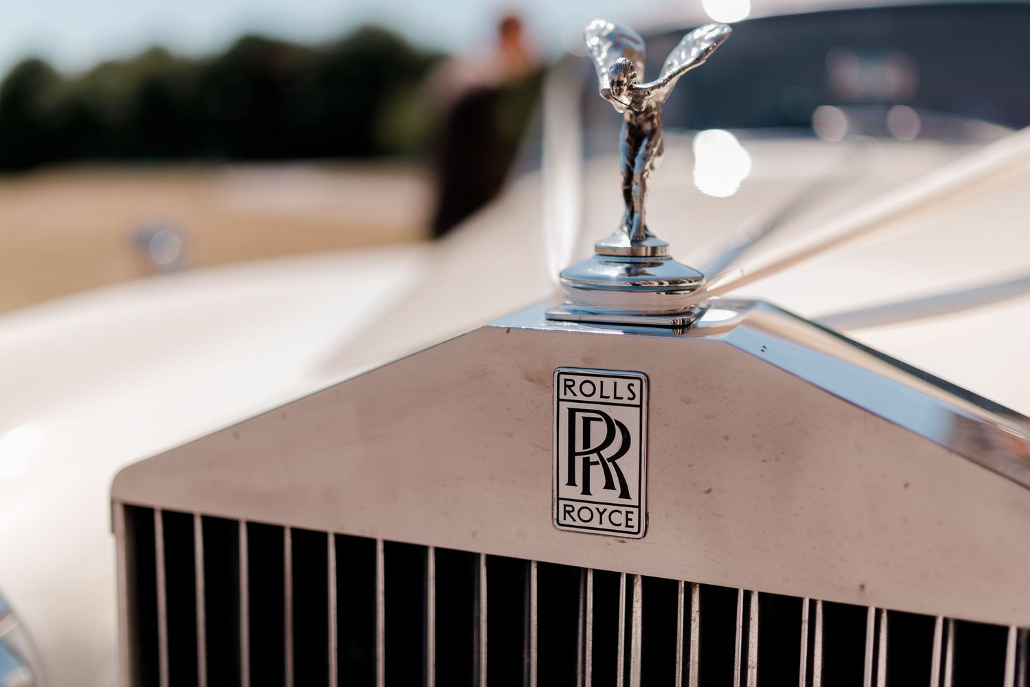 Close up detail shot of a Rolls Royce hood ornament and grille at a luxury wedding.