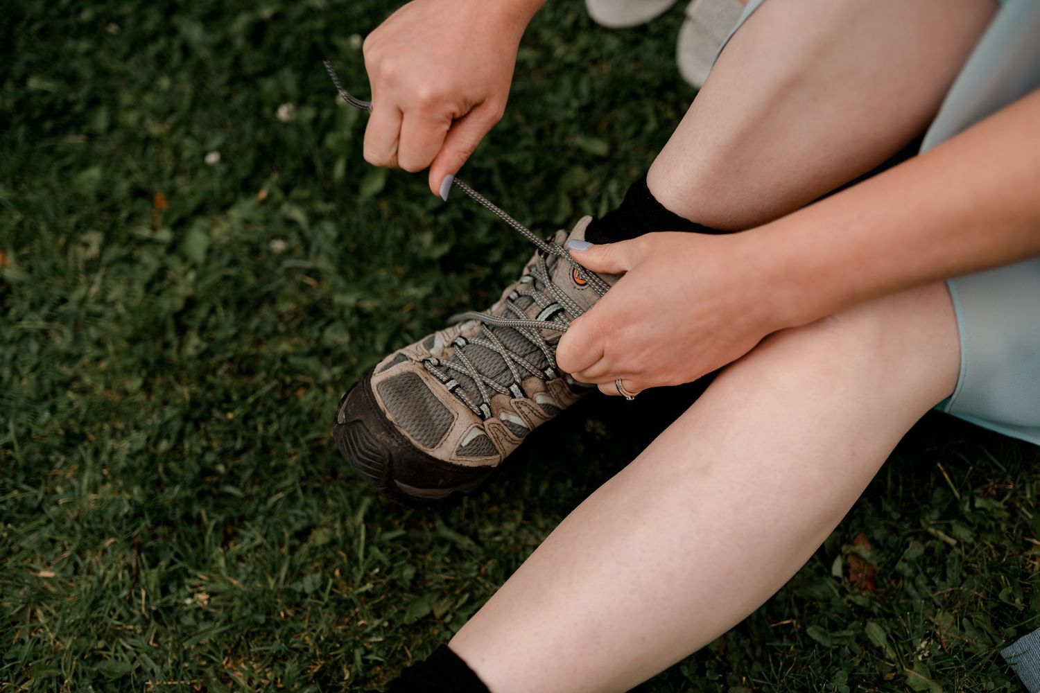 A series of images showing someone applying insect repellent spray to bare legs and feet outdoors on grass.