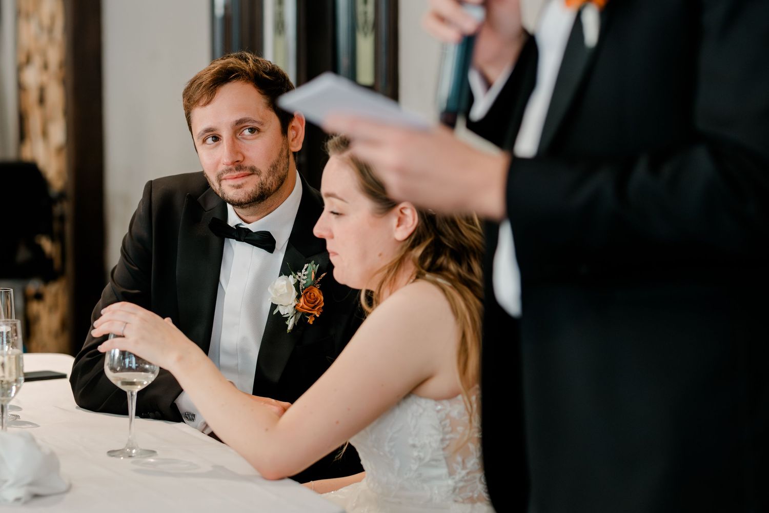 Wedding guests raise champagne glasses in a toast at an elegant reception celebration.
