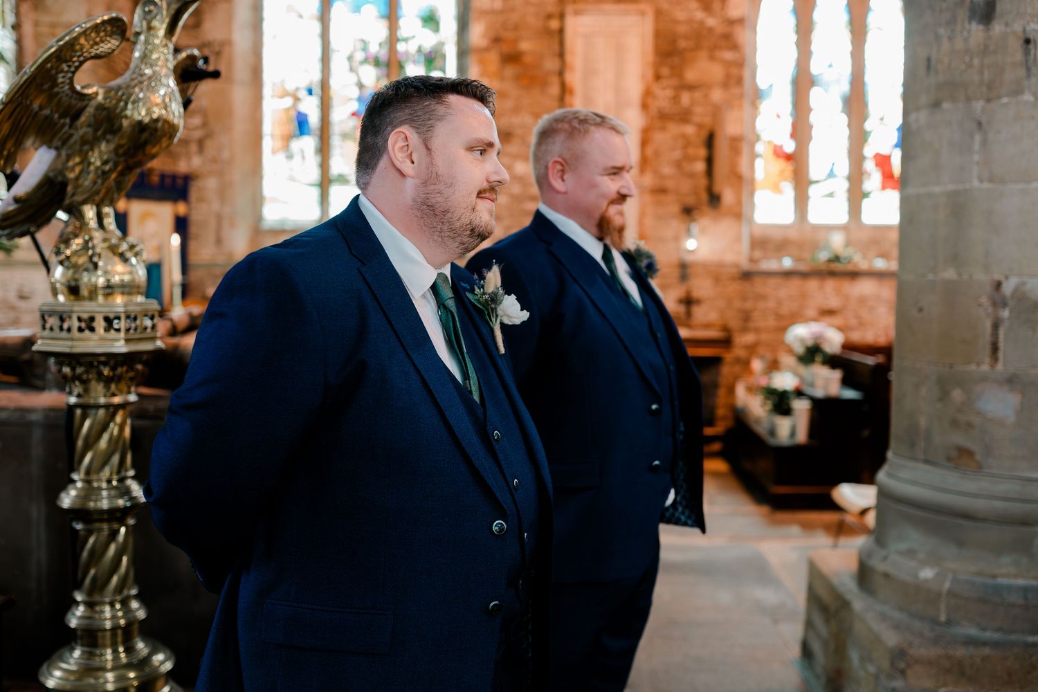 Wedding couple shares intimate moments in a historic stone church with stained glass windows.