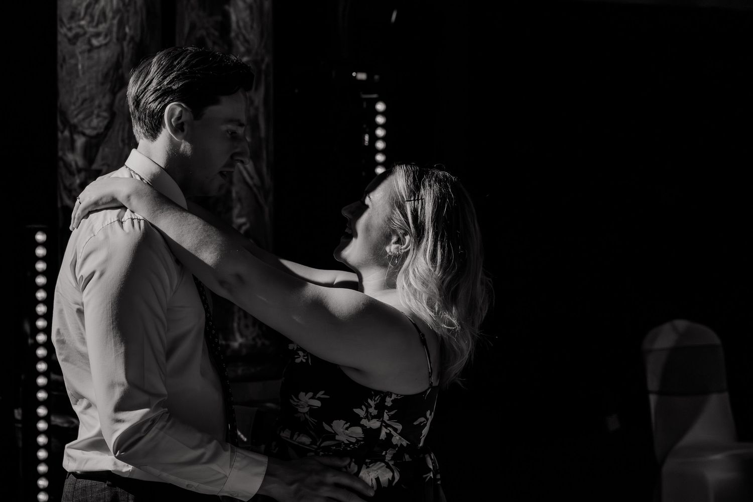 Romantic black and white photo of couple slow dancing at wedding reception.