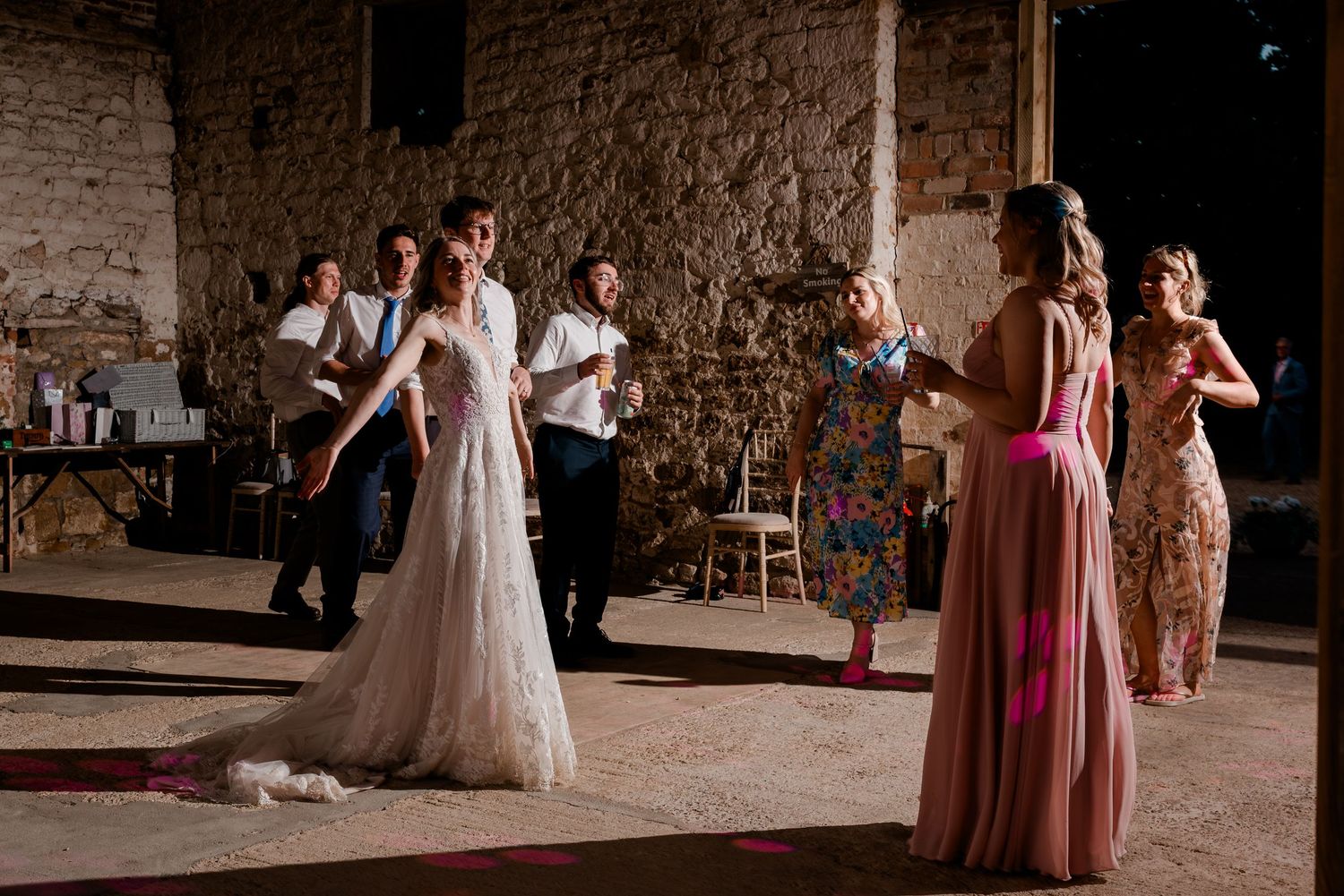 Wedding reception dance party scene in rustic stone barn venue with flowing gowns.