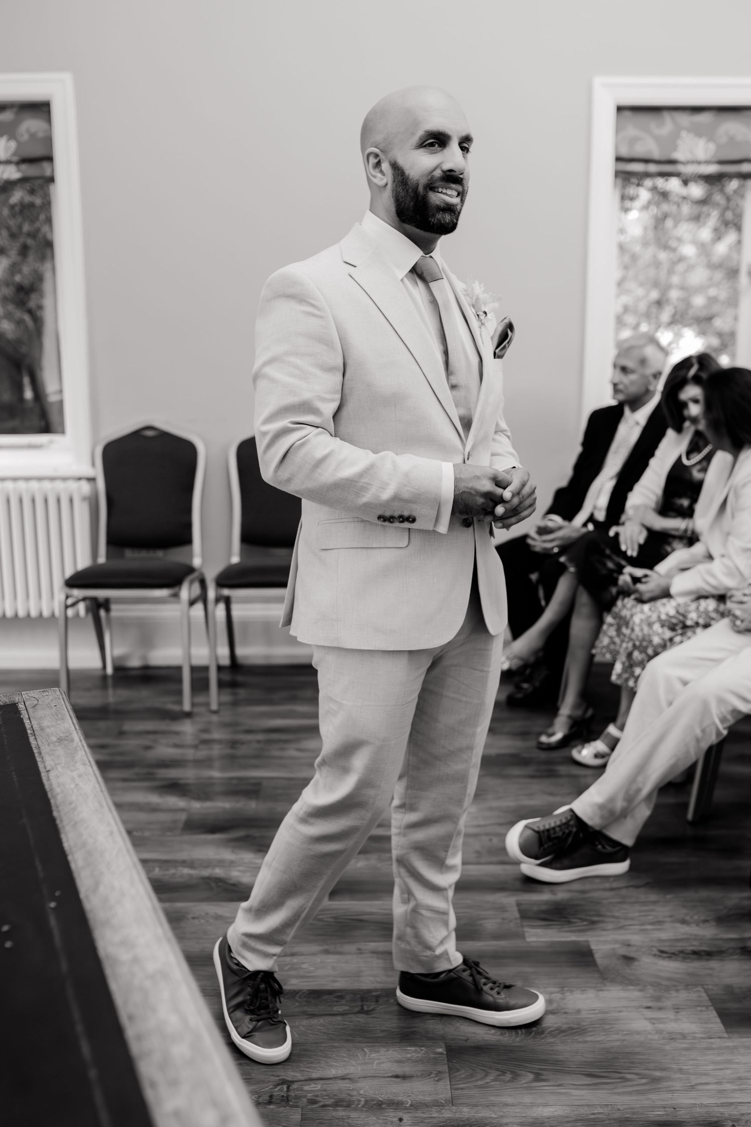 Close-up black and white detail shots of dress shoes and light colored pants on wooden floor.