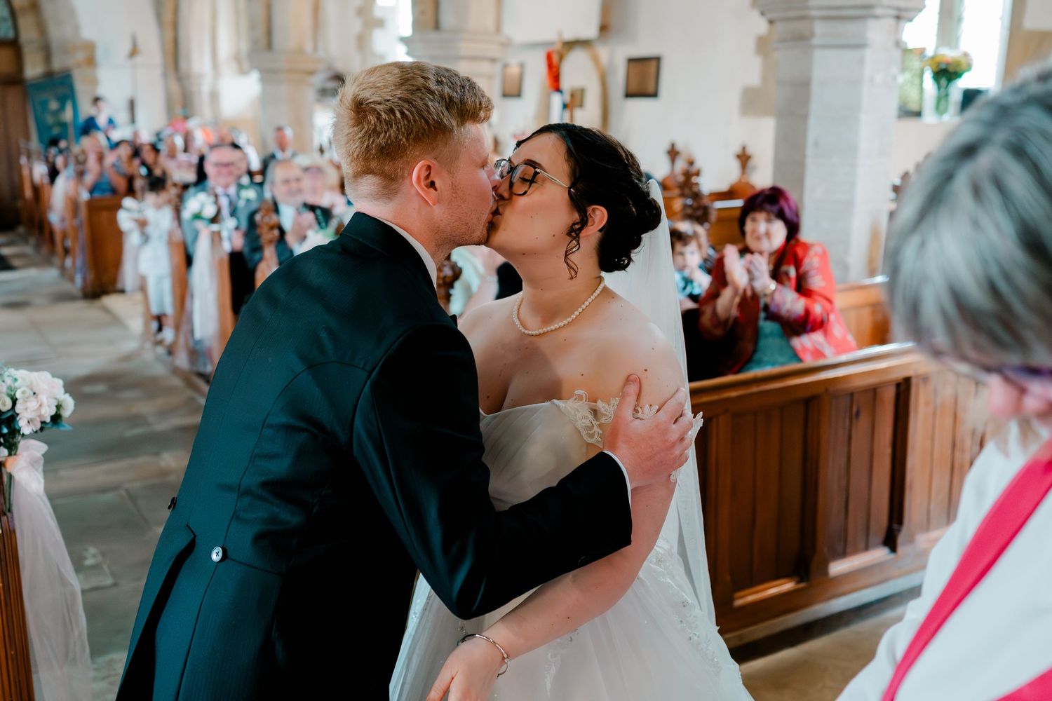 Bride and groom sharing their first kiss at the altar during a church wedding ceremony.