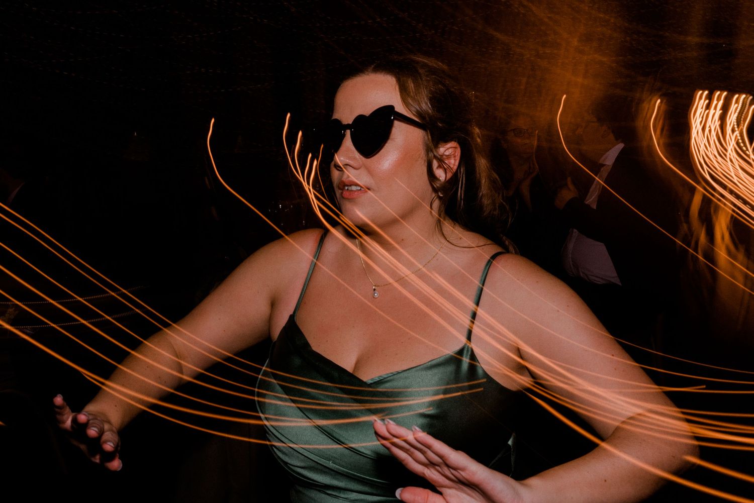 Long exposure photo captures dance floor movement with light trails at wedding reception.