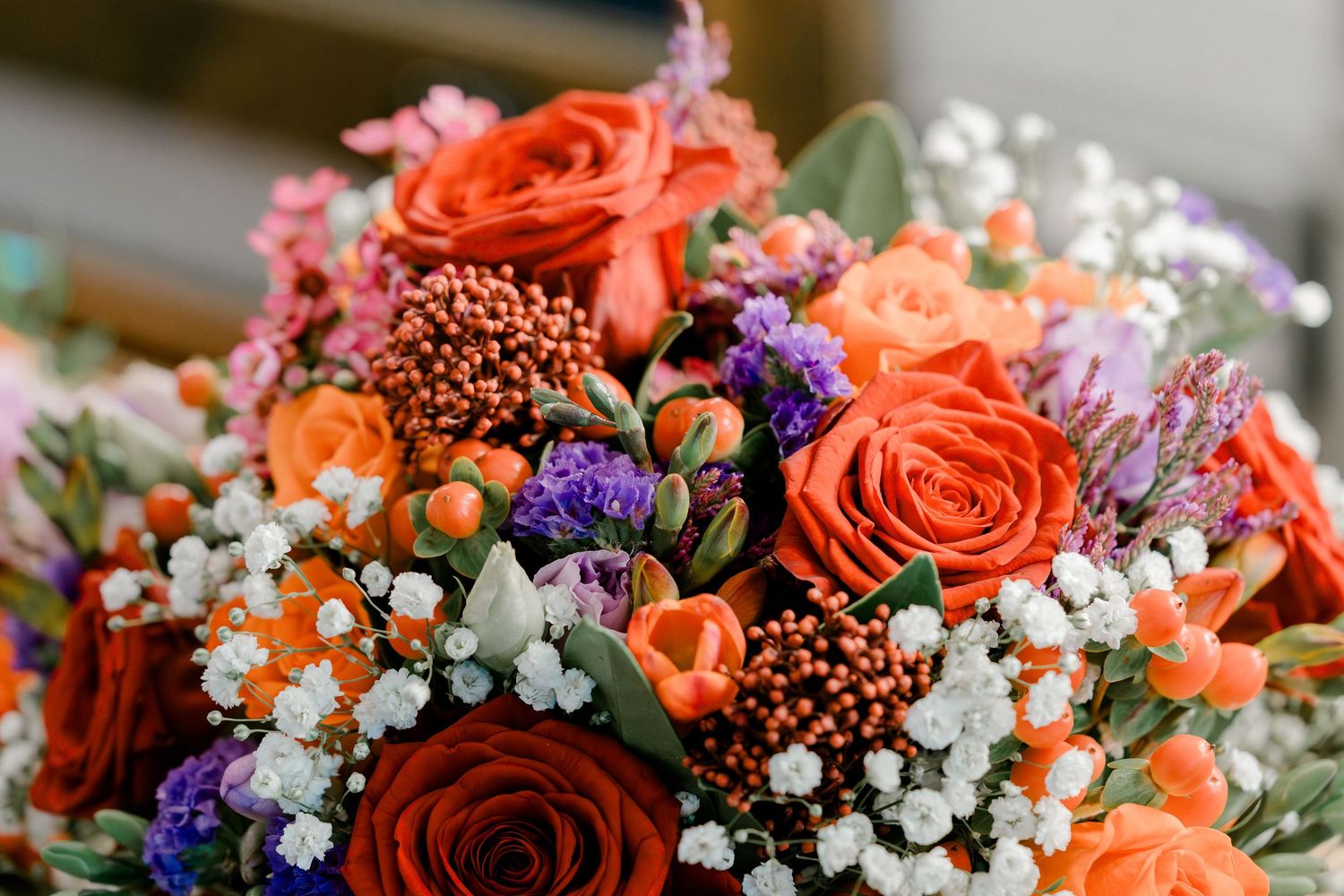 Vibrant bridal bouquet with orange roses, purple flowers, and baby's breath.