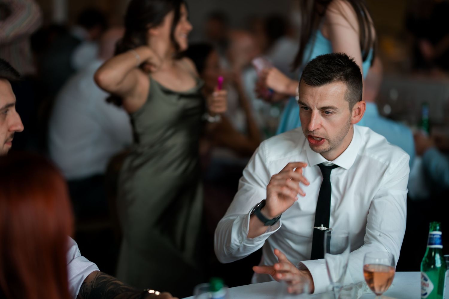Wedding guests enjoying drinks and conversation at an evening reception.