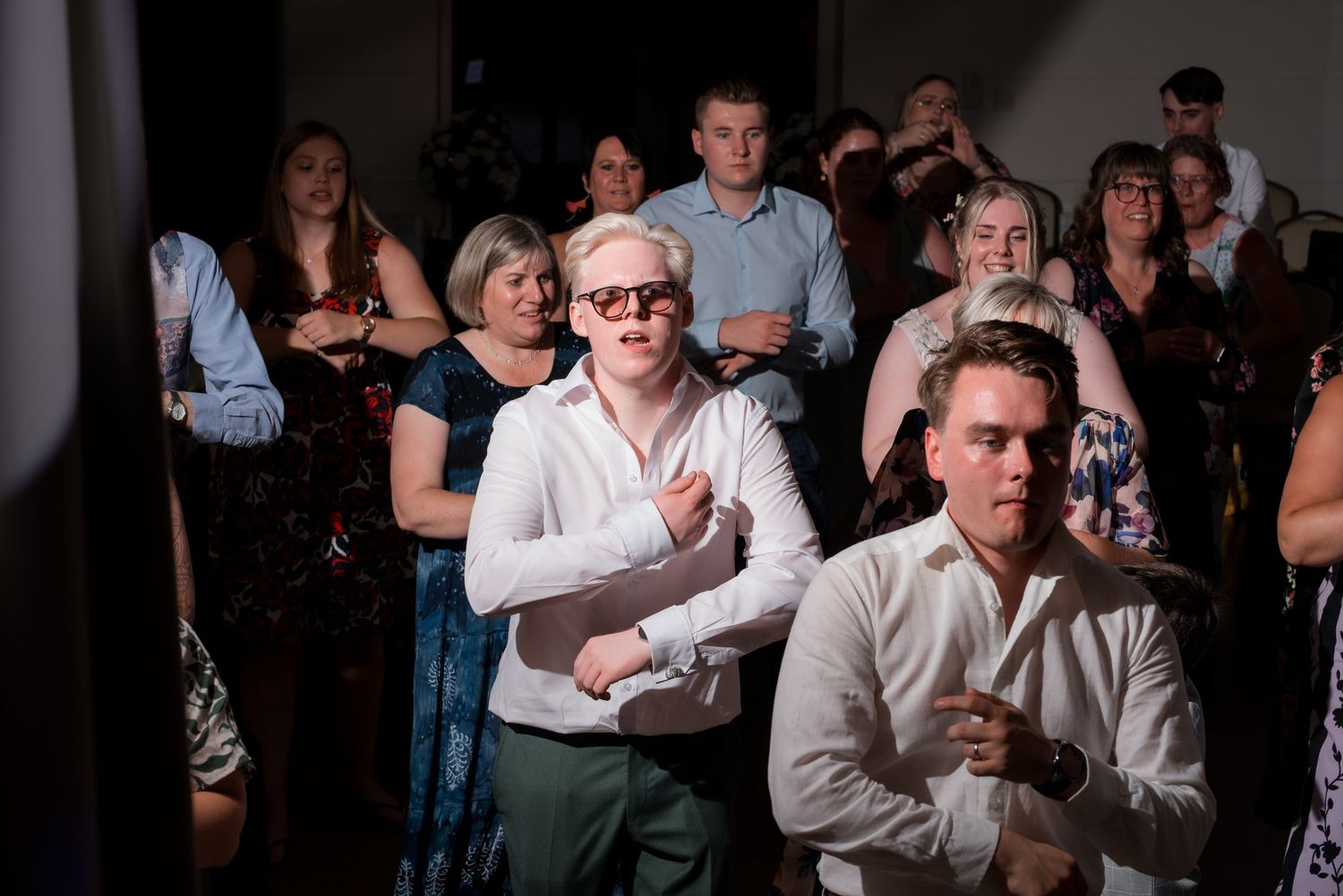 Wedding guests watch intently during an emotional reception moment.