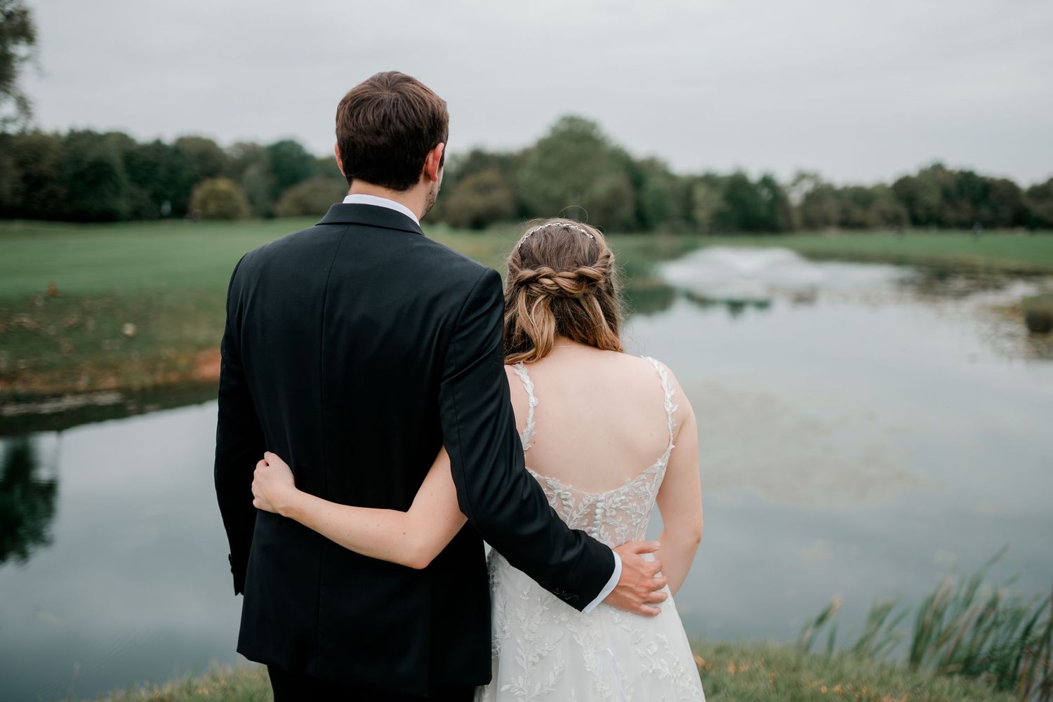 A couple walking together by a scenic lake surrounded by lush greenery.