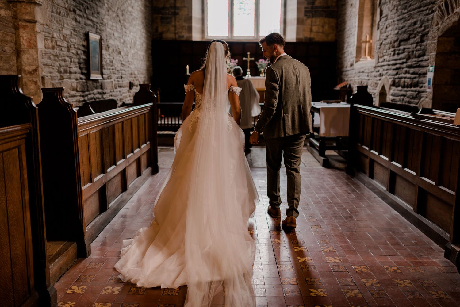 Tender black and white wedding dance moment captured in elegant stone-walled church hallway.