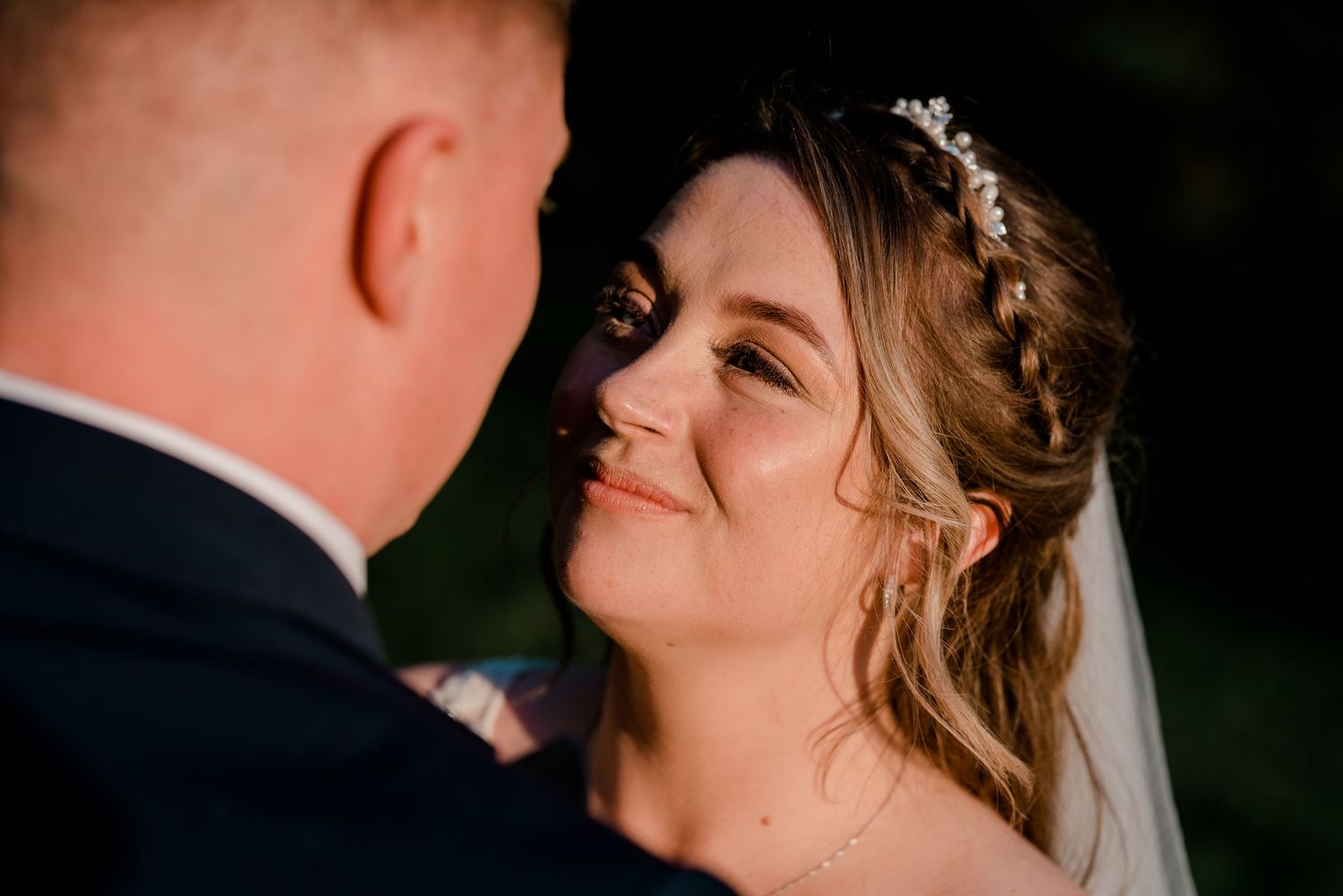 Close portrait of a bride gazing lovingly at her groom during their outdoor wedding celebration.