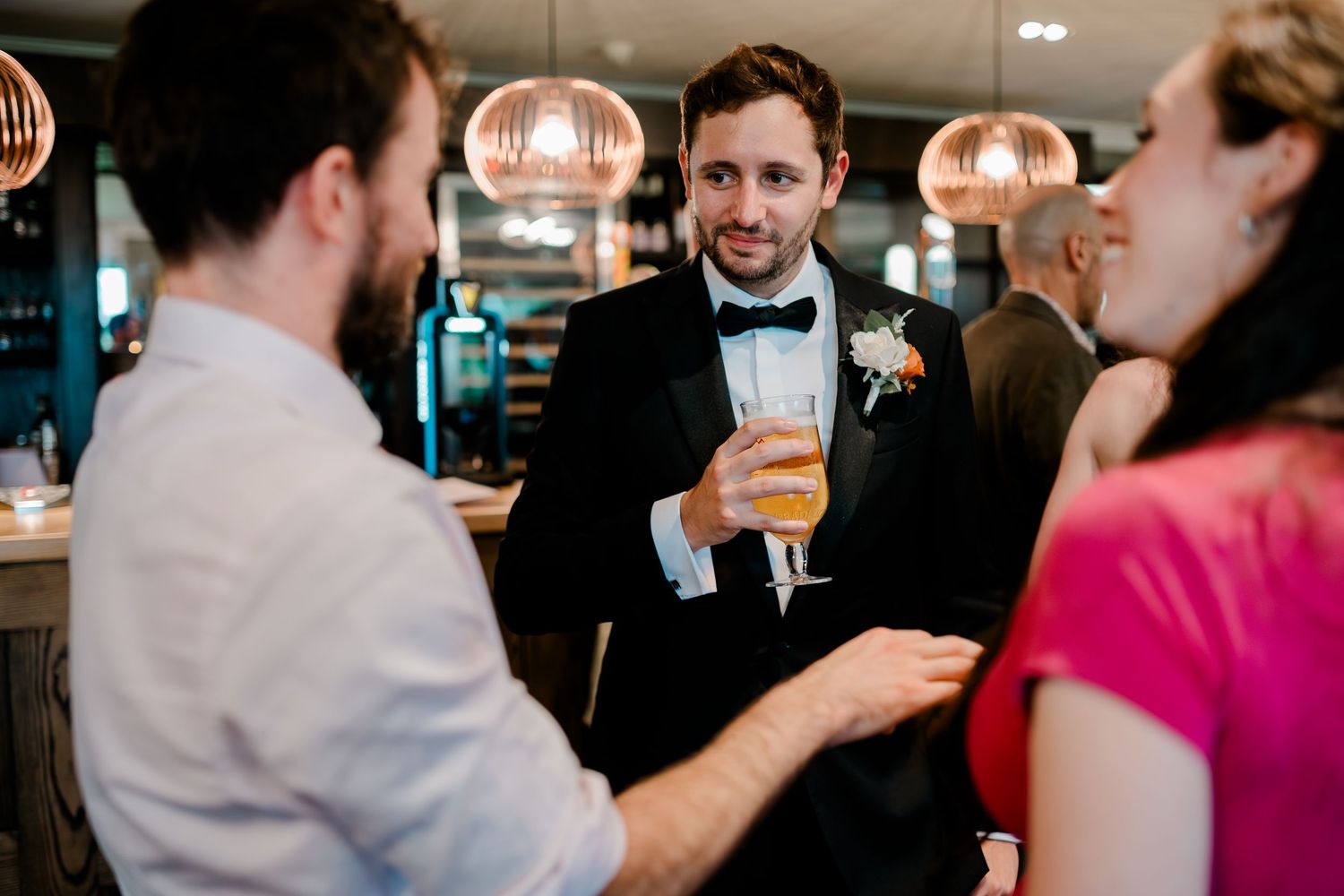 A group of people socializing and drinking beers at an indoor gathering.