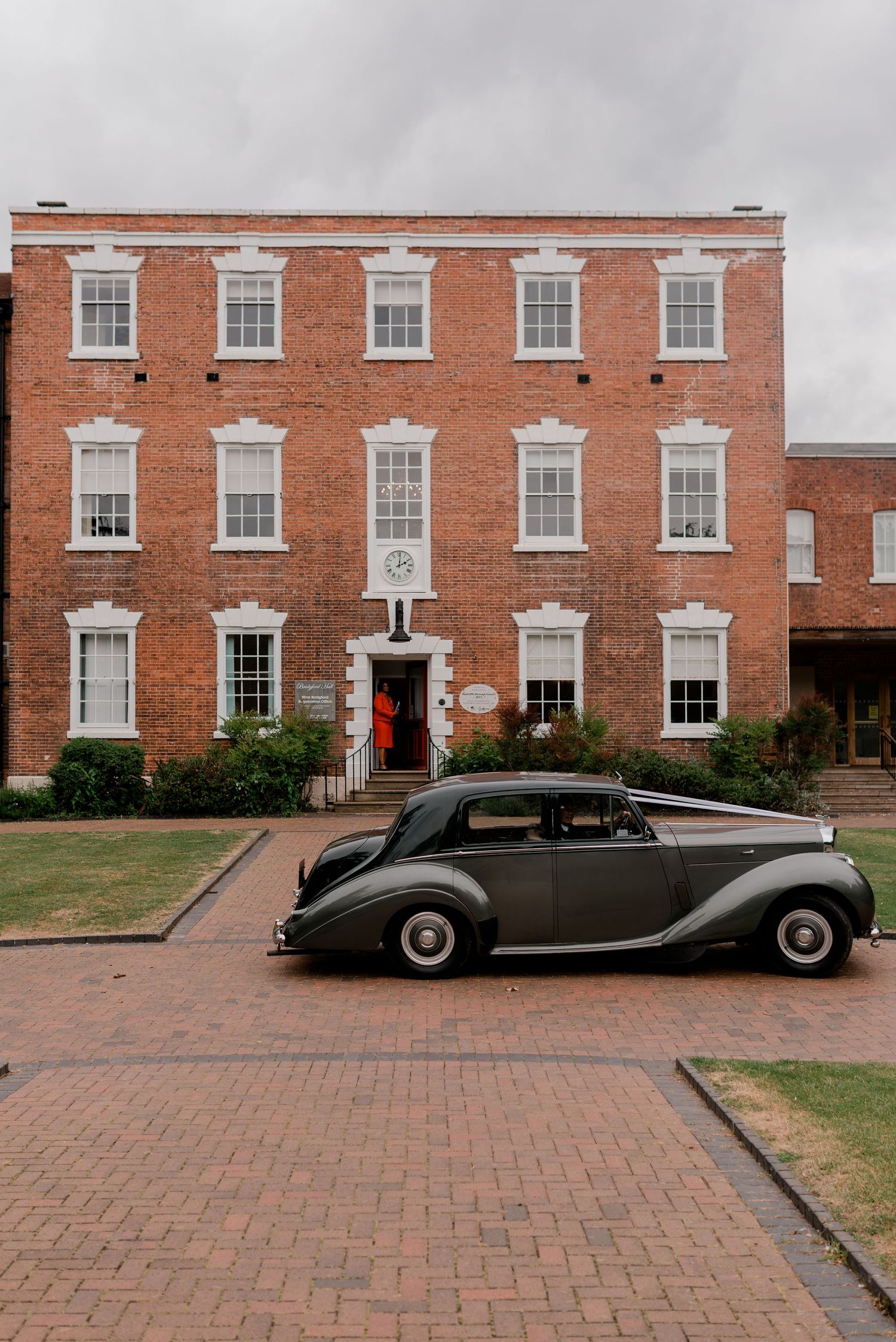 Vintage black Rolls-Royce wedding car parked outside a Georgian red brick venue on a brick driveway.