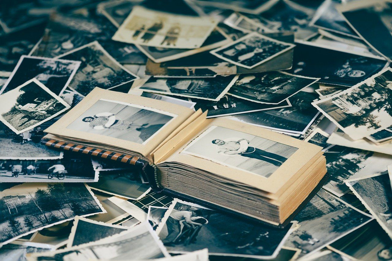 Vintage black and white photographs spread out with photo album in center.