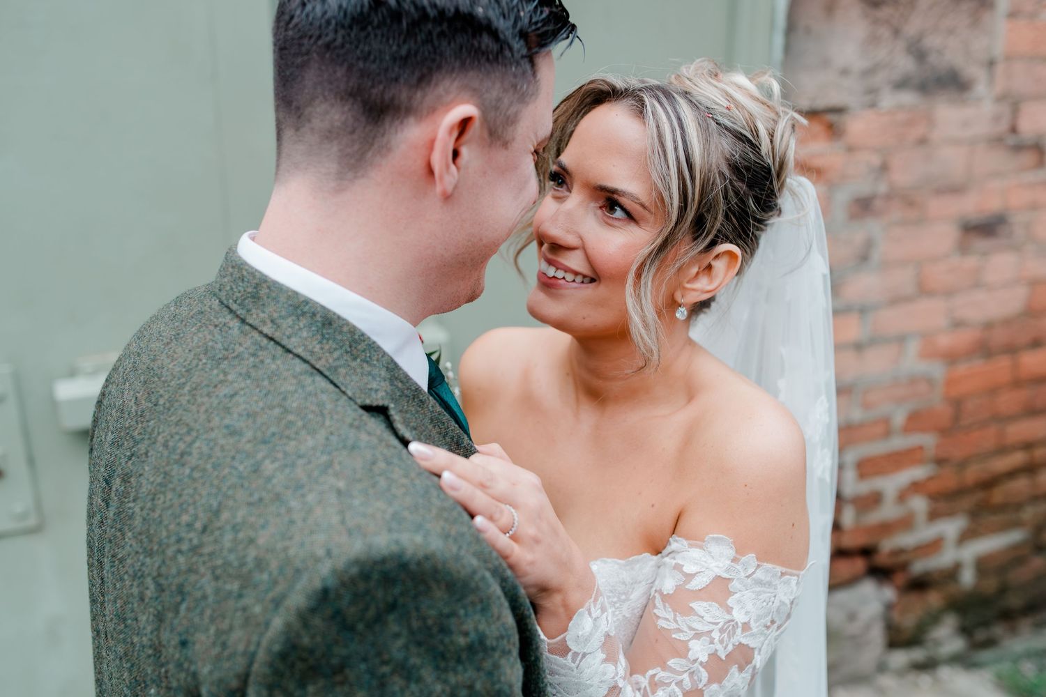Bride smiling at groom in an intimate moment against a green door at their wedding.
