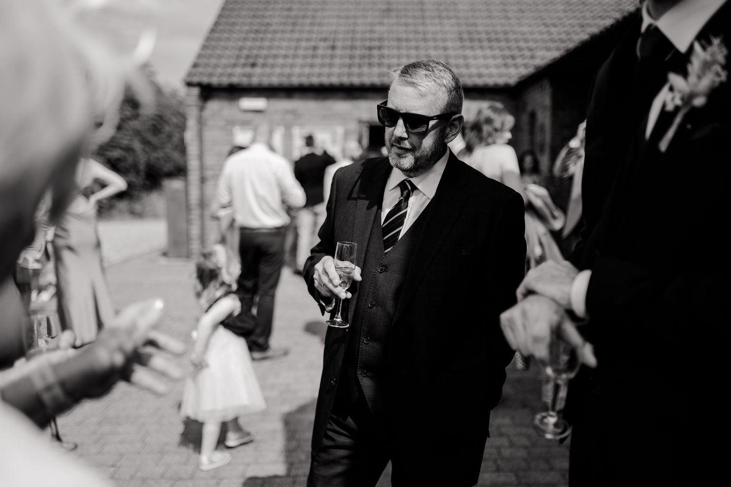 Black and white photo of wedding guests dancing and celebrating at a reception.