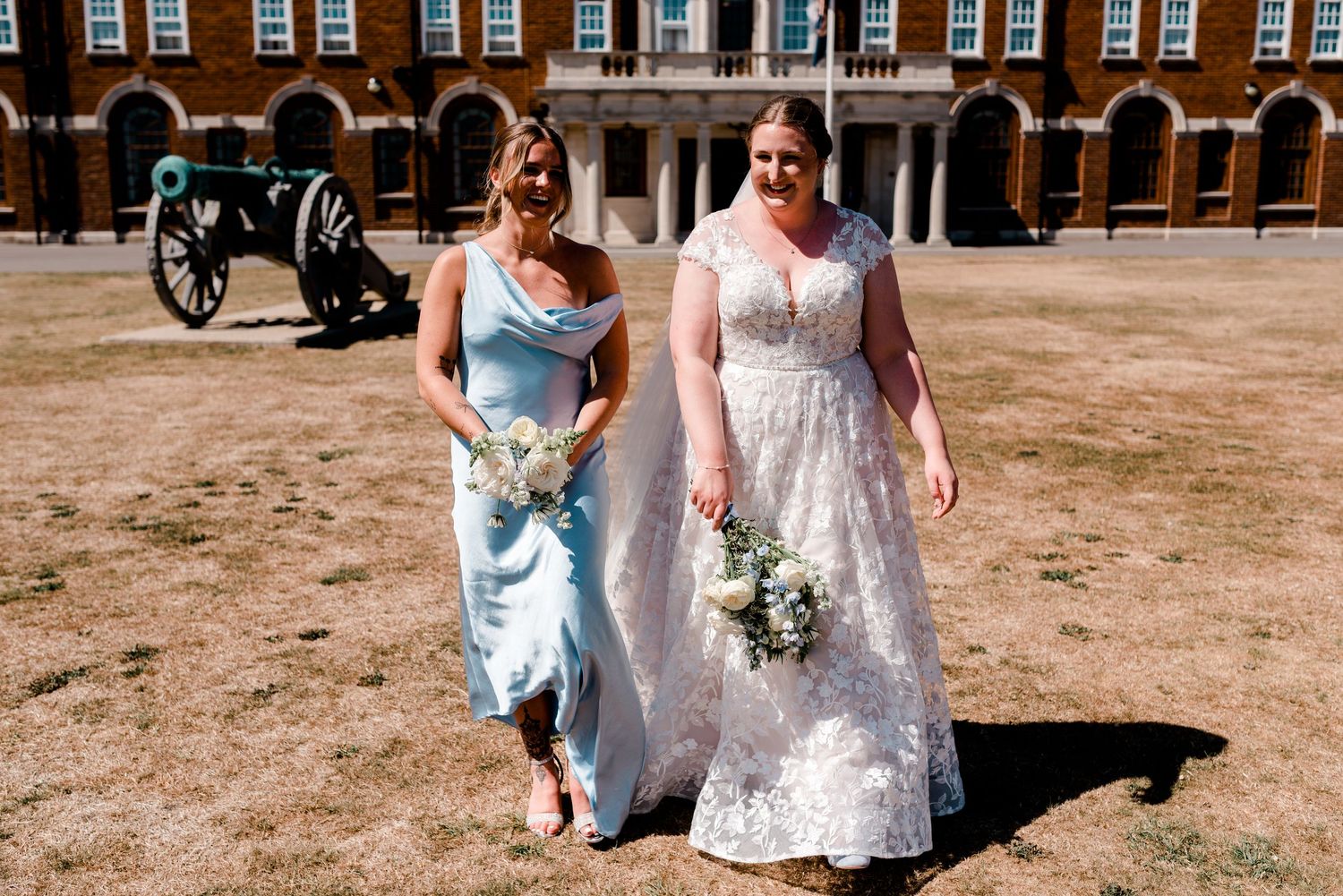Wedding party enjoys outdoor photos near historic brick buildings.