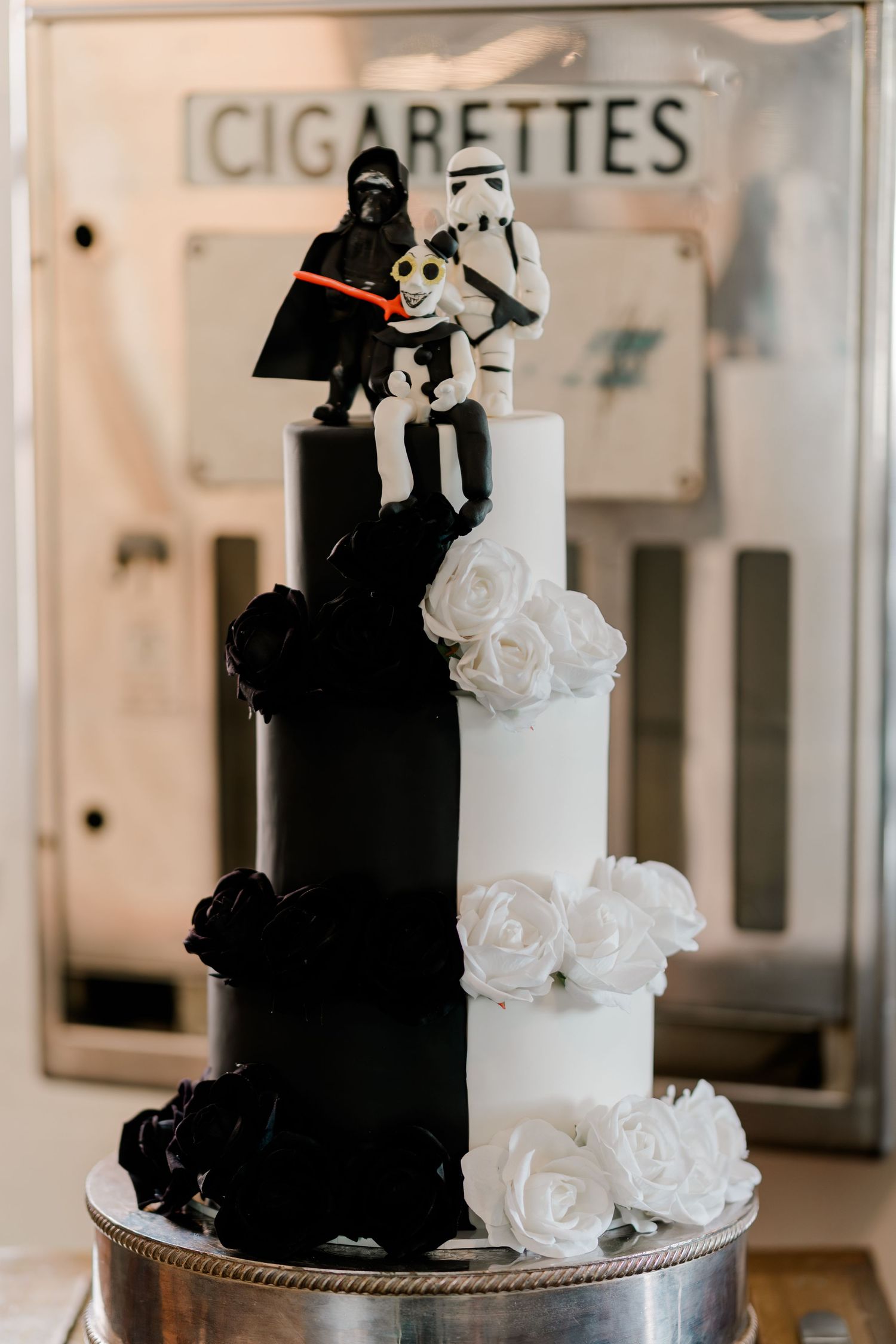 Star Wars wedding cake with Darth Vader and Stormtrooper toppers, half black half white tiers with roses.