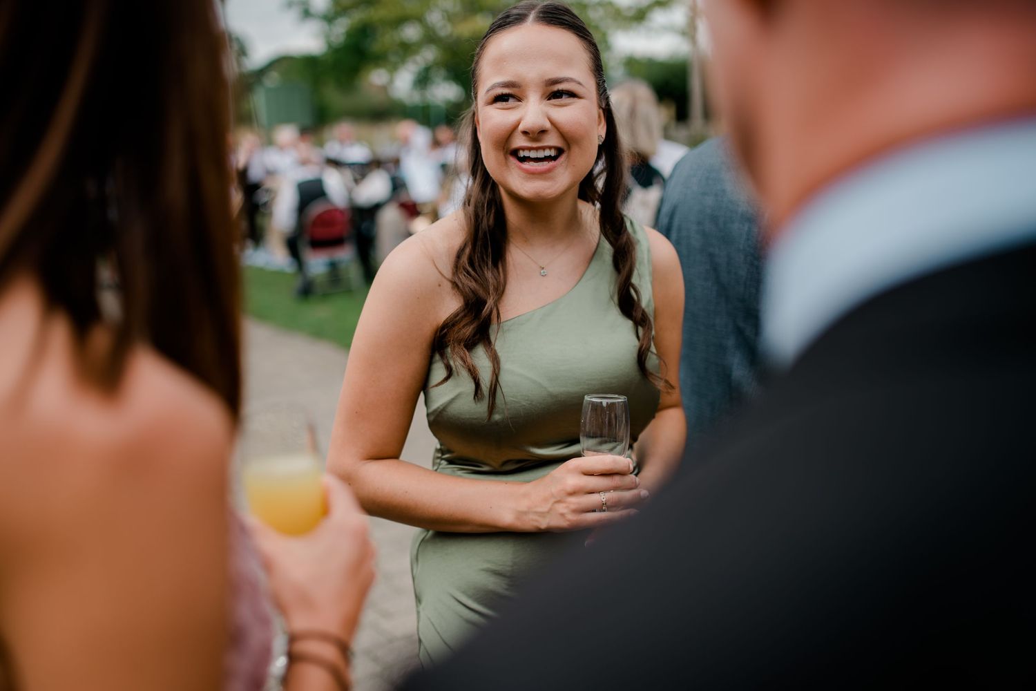 Wedding party members sharing candid laughs and smiles during outdoor celebration.