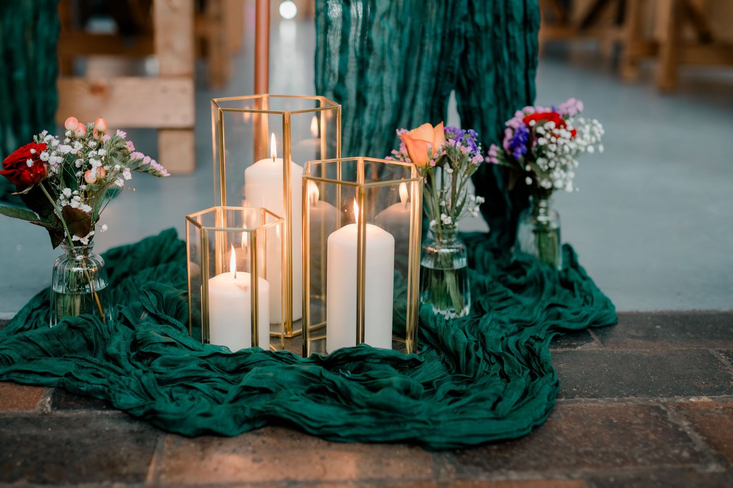 Wedding decor with white pillar candles, gold lanterns, and teal fabric.