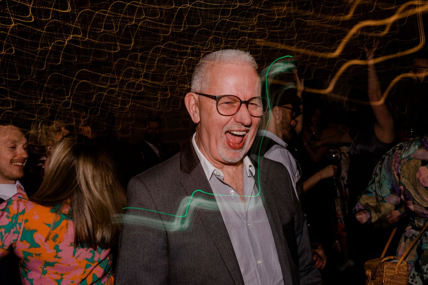 Guest enjoying the wedding celebration with a hearty laugh under ambient lighting.