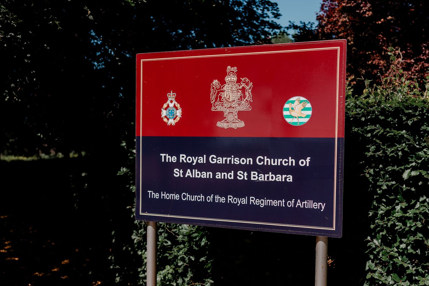 Red and blue church welcome signs displayed on posts outside a religious building entrance.