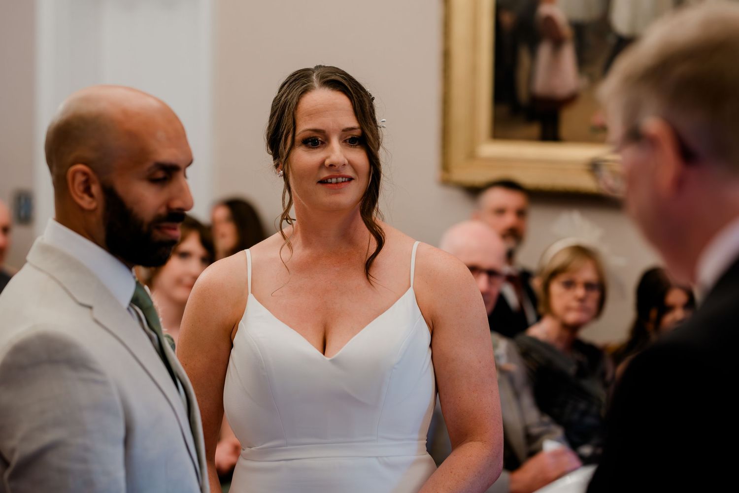 A couple shares their first dance at an elegant wedding reception surrounded by guests in a formal venue.