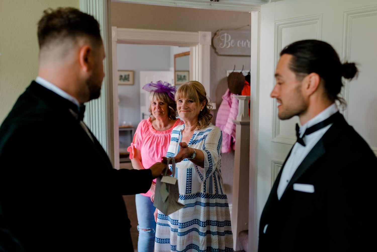Wedding preparations in a doorway with people in formal attire.