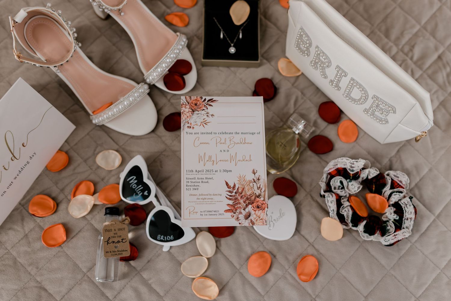 Flat lay of romantic wedding stationery with orange pumpkins, black hearts, and floral designs on beige background.