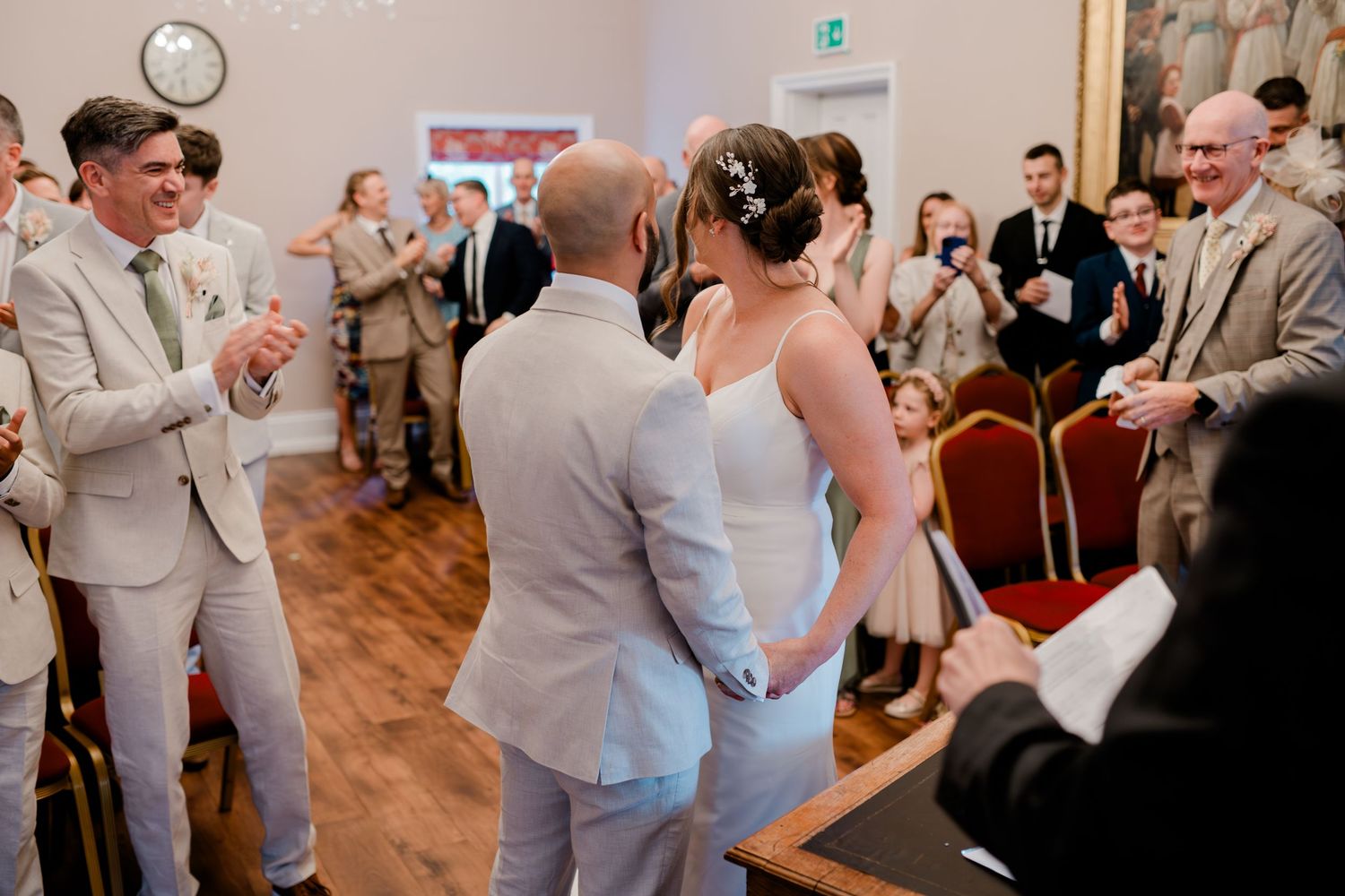 A joyous celebration during a wedding ceremony in an elegant indoor venue with hardwood floors.