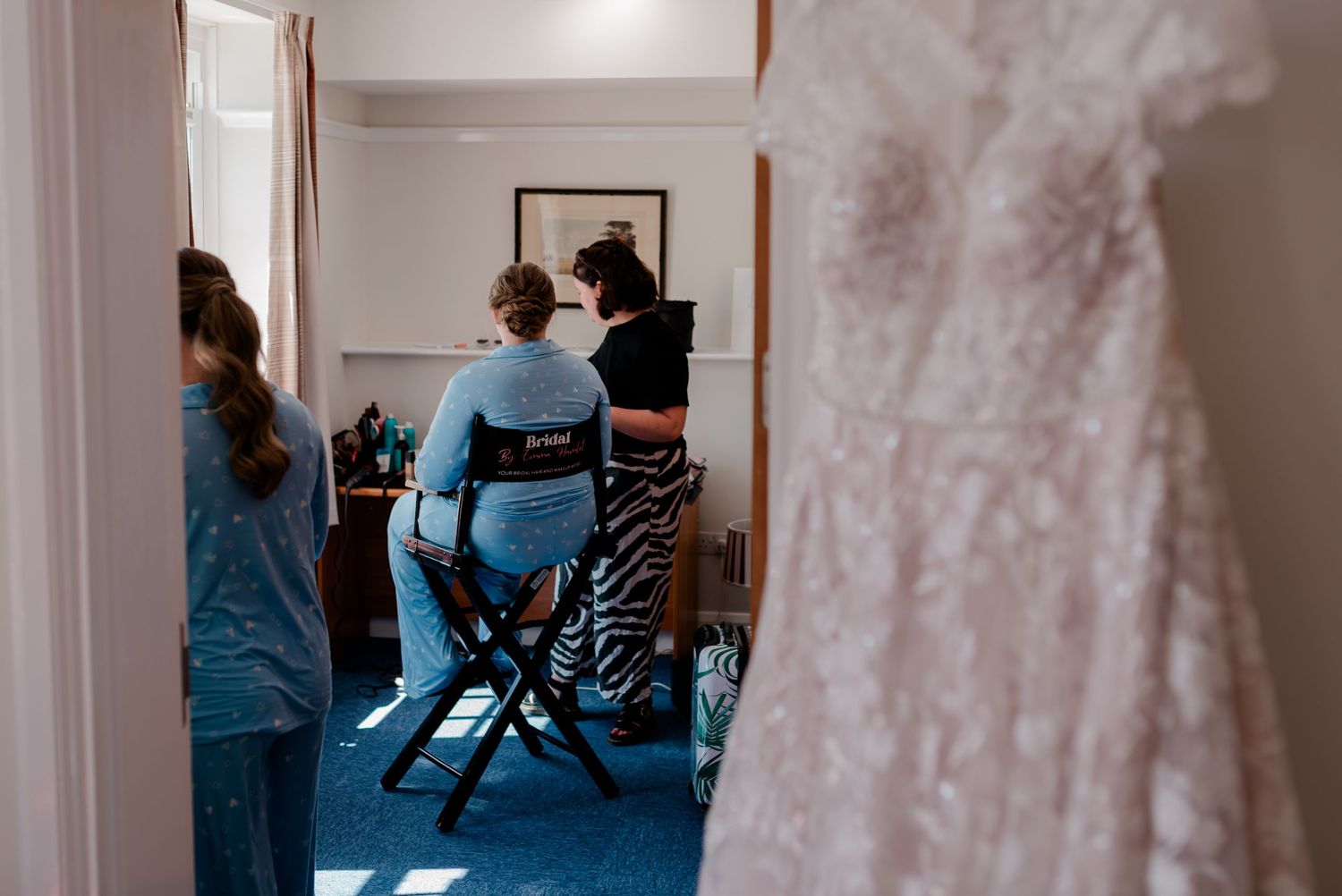 Behind the scenes view of a makeup and hair styling session with professionals working in a bright room.