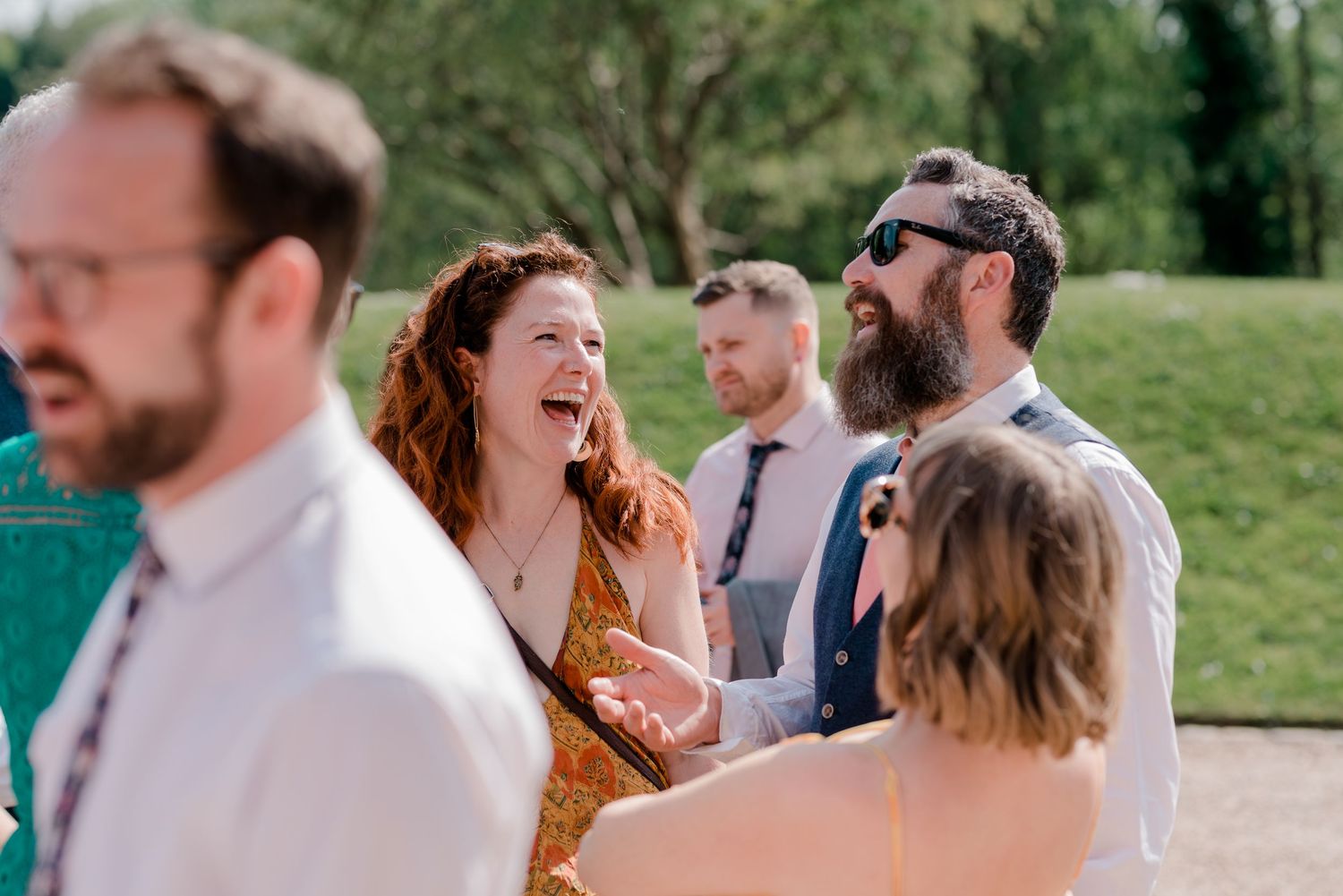 Wedding celebration candid moments showing joyful guests laughing and interacting outdoors.