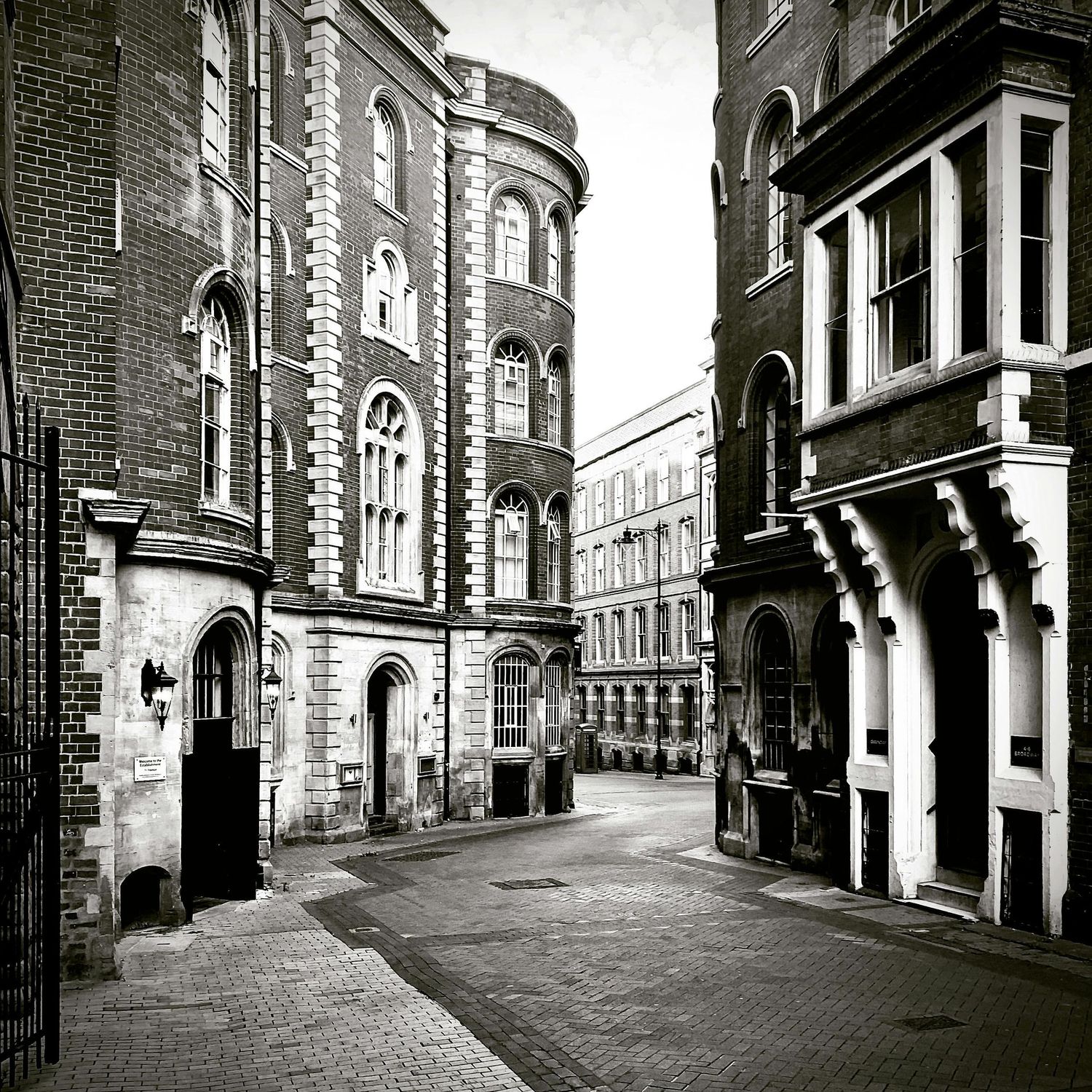 Historic architectural street view of ornate Victorian buildings with arched windows and brick facades.