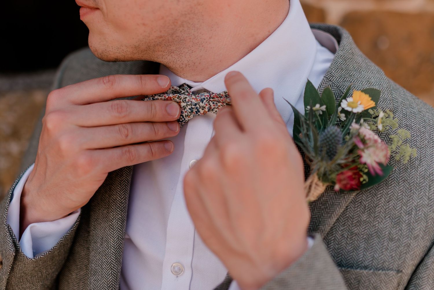 Five close-up shots showing hands adjusting boutonnieres with delicate flowers and greenery on grey suit lapels.