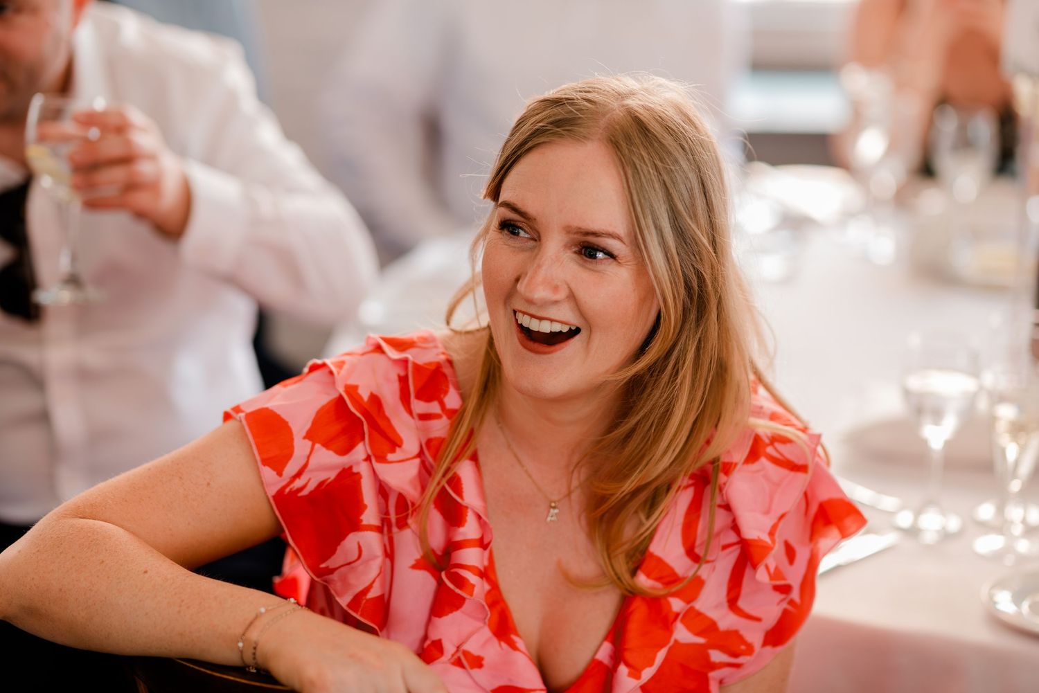 Wedding reception guests laughing and socializing at decorated indoor venue.