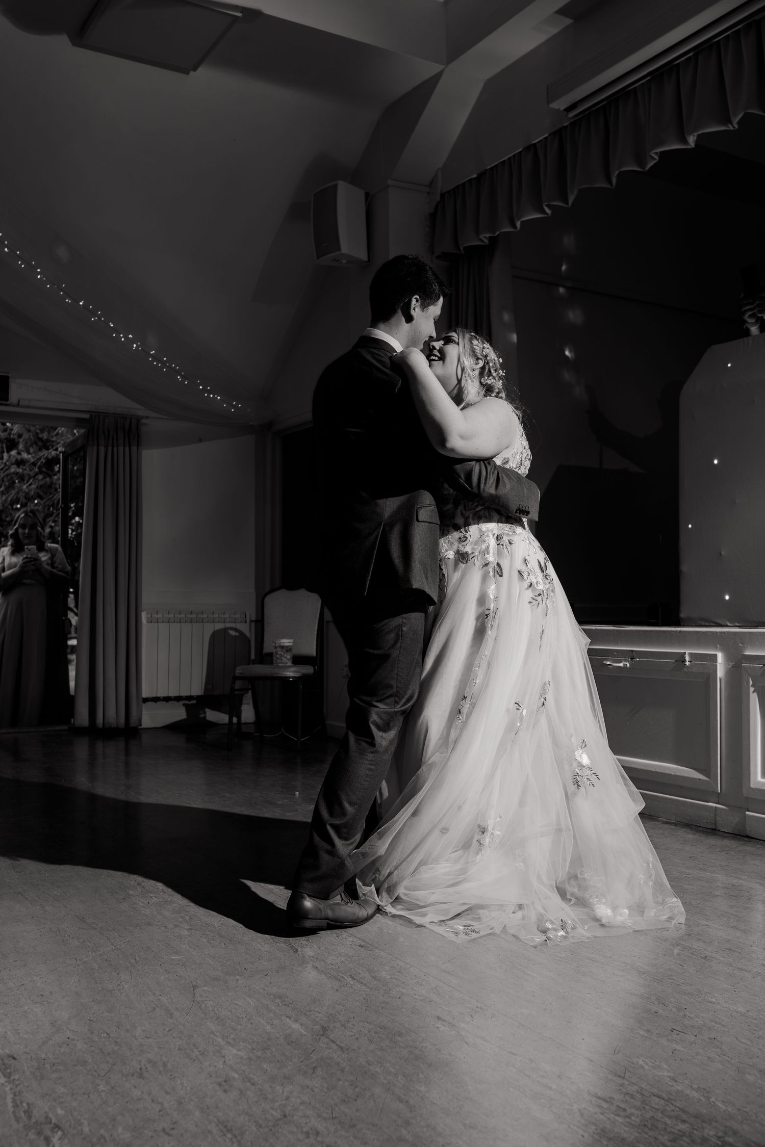 Black and white photo of a romantic slow dance on an illuminated dance floor.