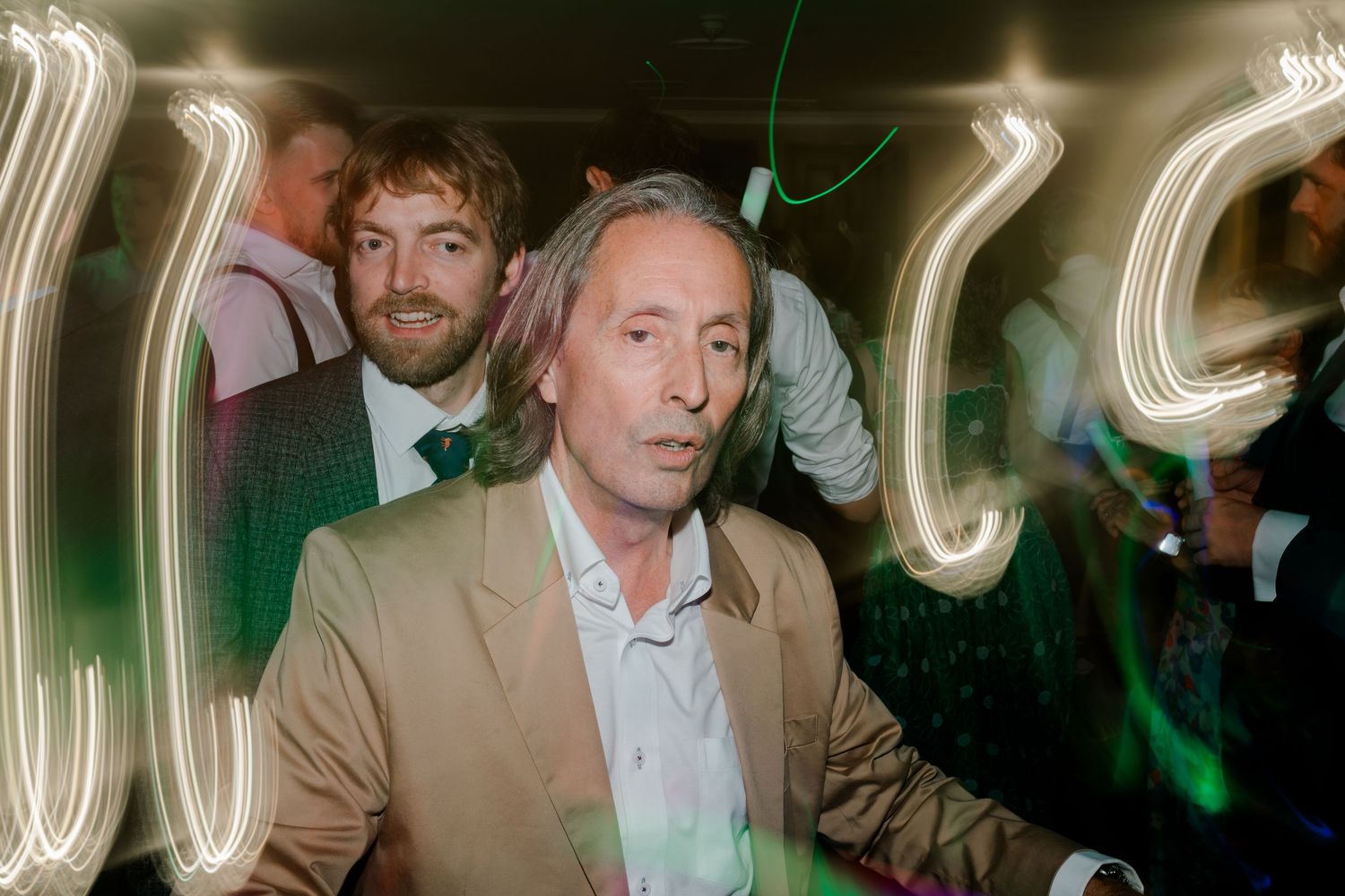 People dancing and celebrating at a wedding reception with blurred light trails creating a dynamic party atmosphere.