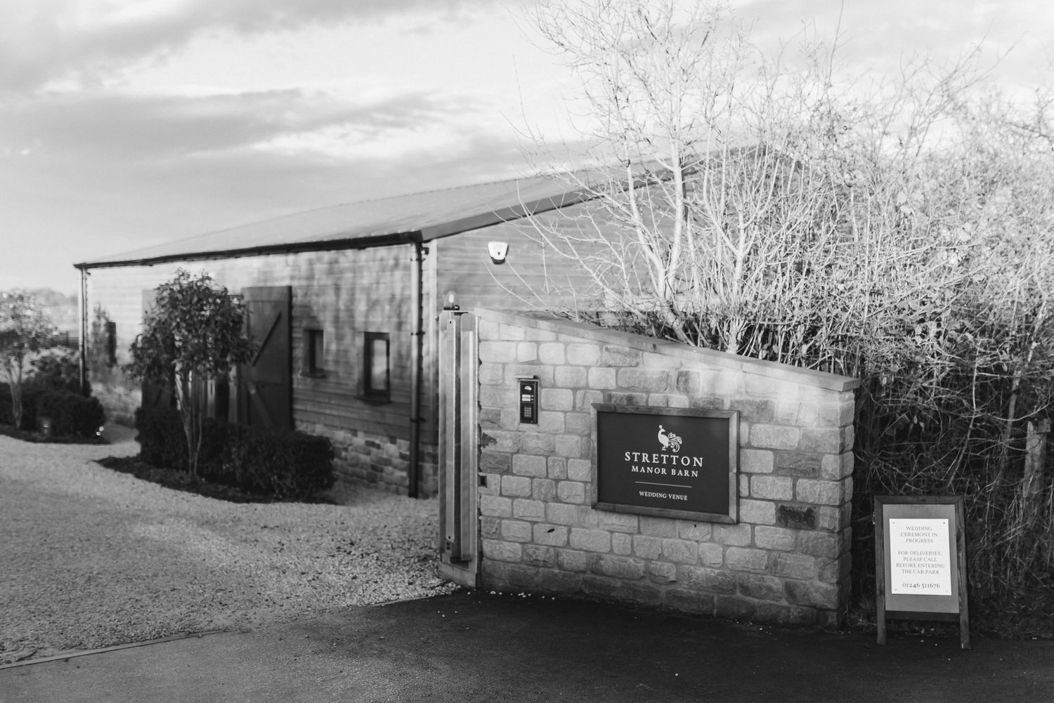 Black and white exterior shot of Stretton Manor Barn wedding venue entrance with stone walls and gate.