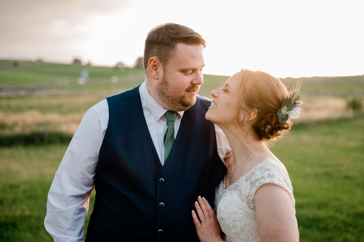 Couple embraces on a grassy hilltop during their wedding day photoshoot.