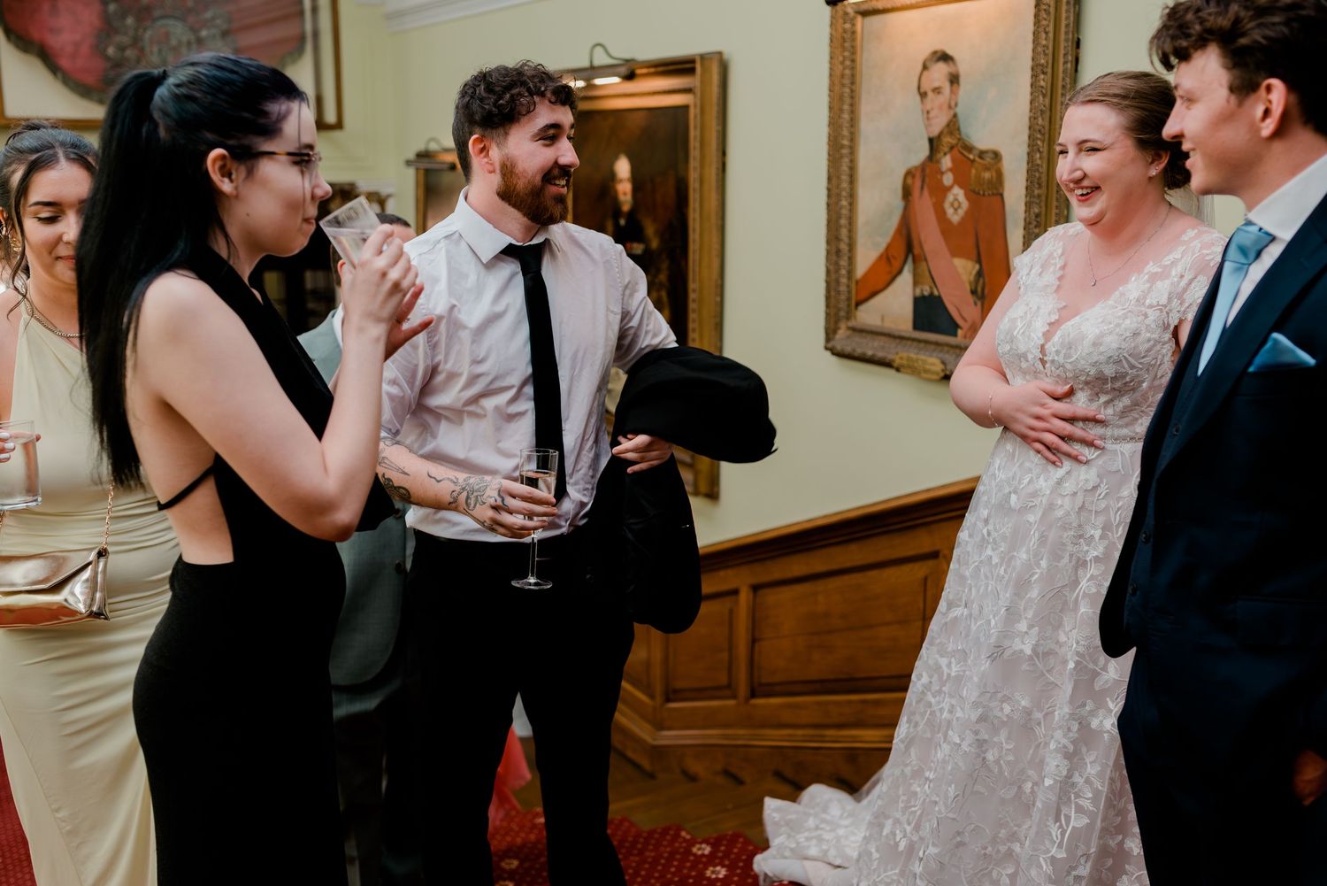 Wedding reception guests mingle and dance in an elegant room with artwork.